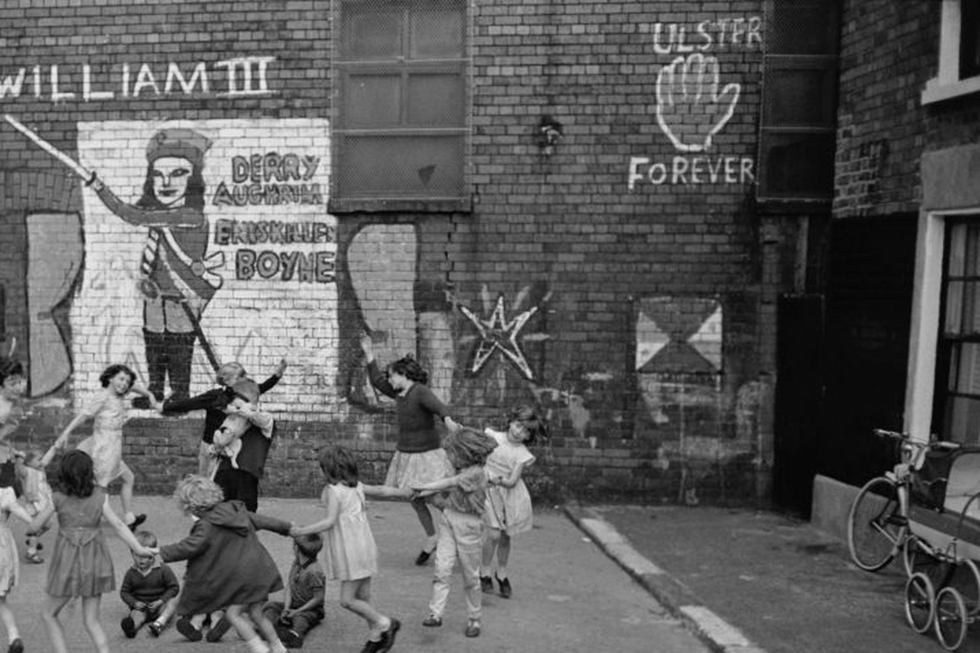 Dieses Porträtfoto des Gesellschaftsfotografen Slim Aarons aus den frühen 1960er Jahren zeigt Kinder, die auf einer mit Graffiti beschmierten Straße mit der Aufschrift 