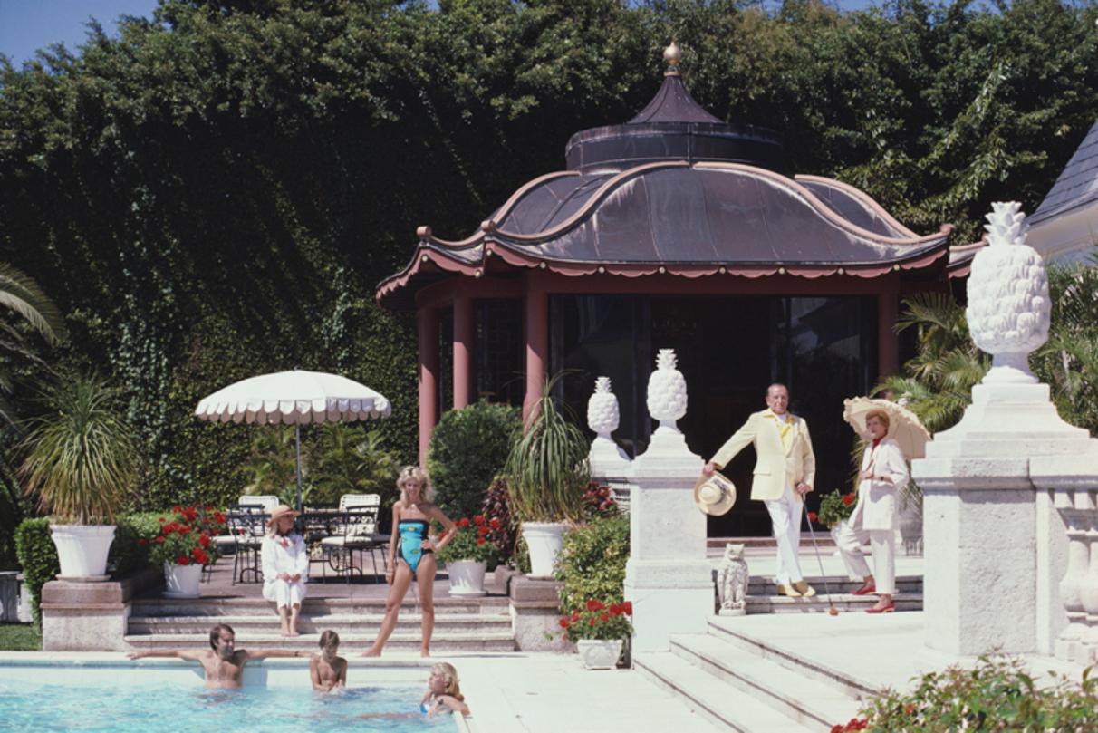 Pagoda Poolhouse 
1985
by Slim Aarons

Slim Aarons Limited Estate Edition

Albin and Margo Lykes Holder (right), with friends by the swimming pool at their home in Palm Beach, Florida, 1985. Behind them is a chinese pagoda poolhouse designed by John