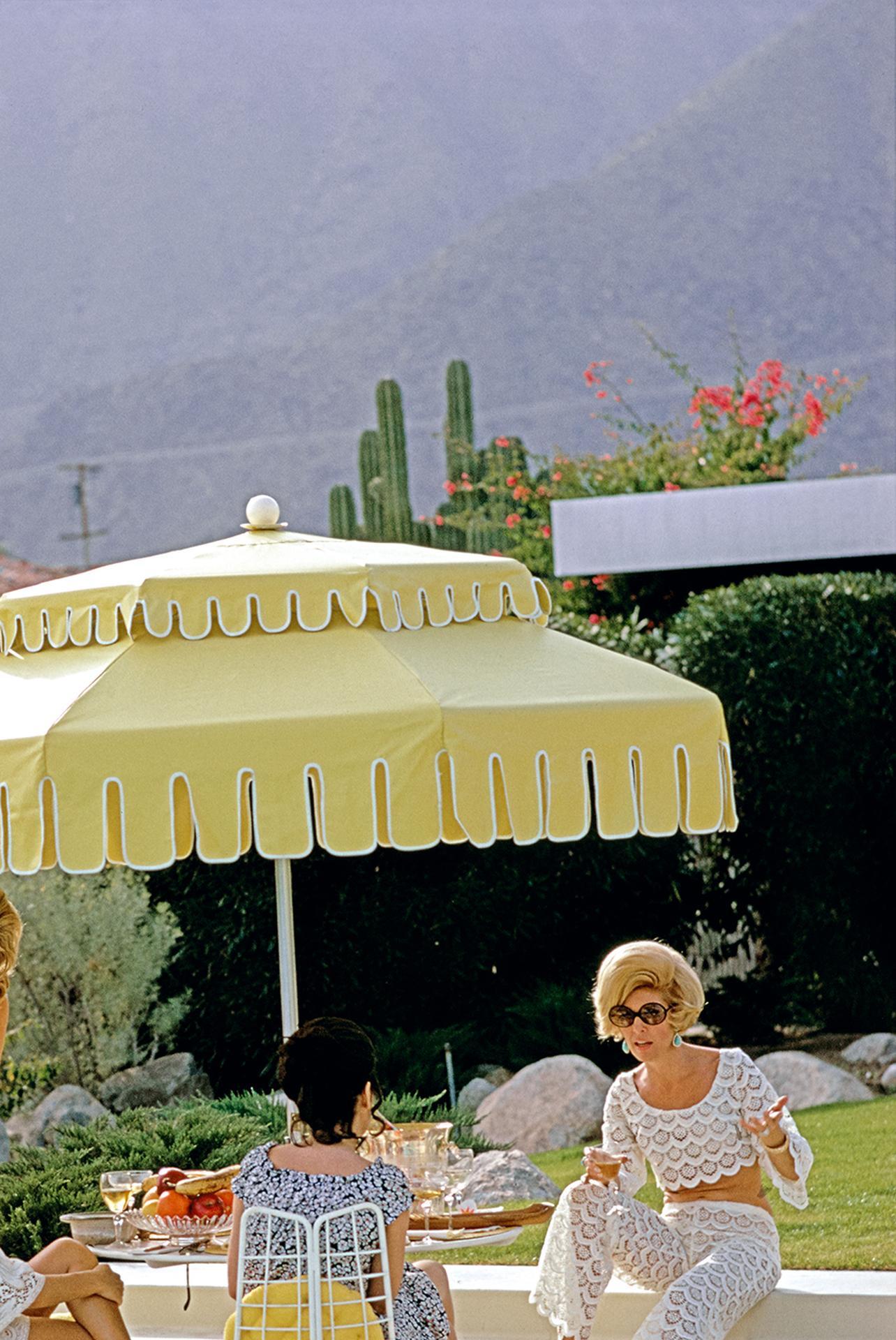 Dieses Porträtfoto von 1970, aufgenommen vom Society-Fotografen Slim Aarons, zeigt Nelda Linsk (links, in gelb), die Frau des Kunsthändlers Joseph Linsk, mit Gästen am Pool des Linsk-Hauses in Palm Springs, Januar 1970. Ganz links mit weißem