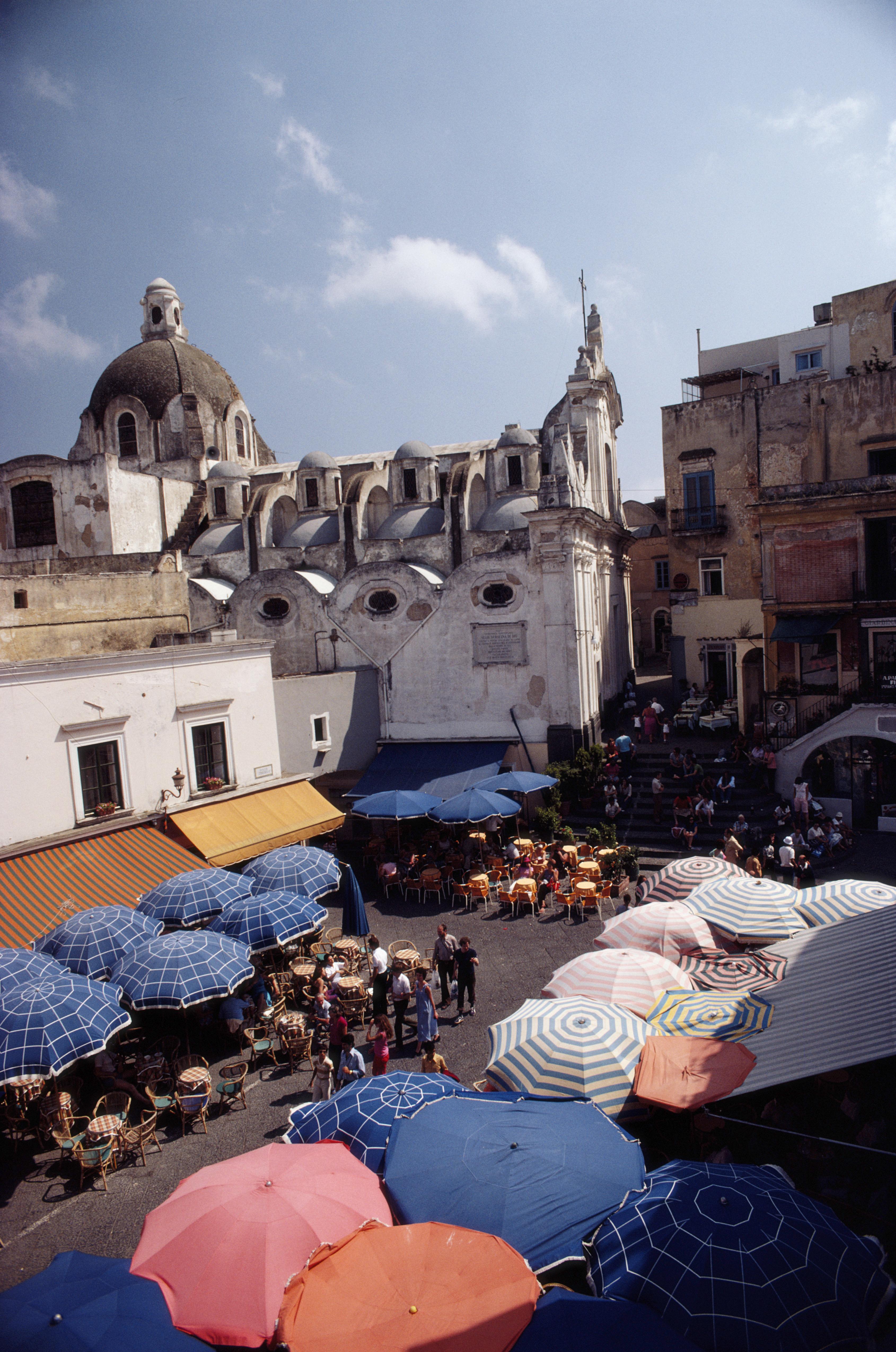 'Piazza Umberto' 1980 Slim Aarons Limited Estate Edition Print 

Aerial view of a parasols shading customers at cafes and restaurants in the Piazza Umberto, on the island of Capri, Italy, in August 1980. 

Produced from the original