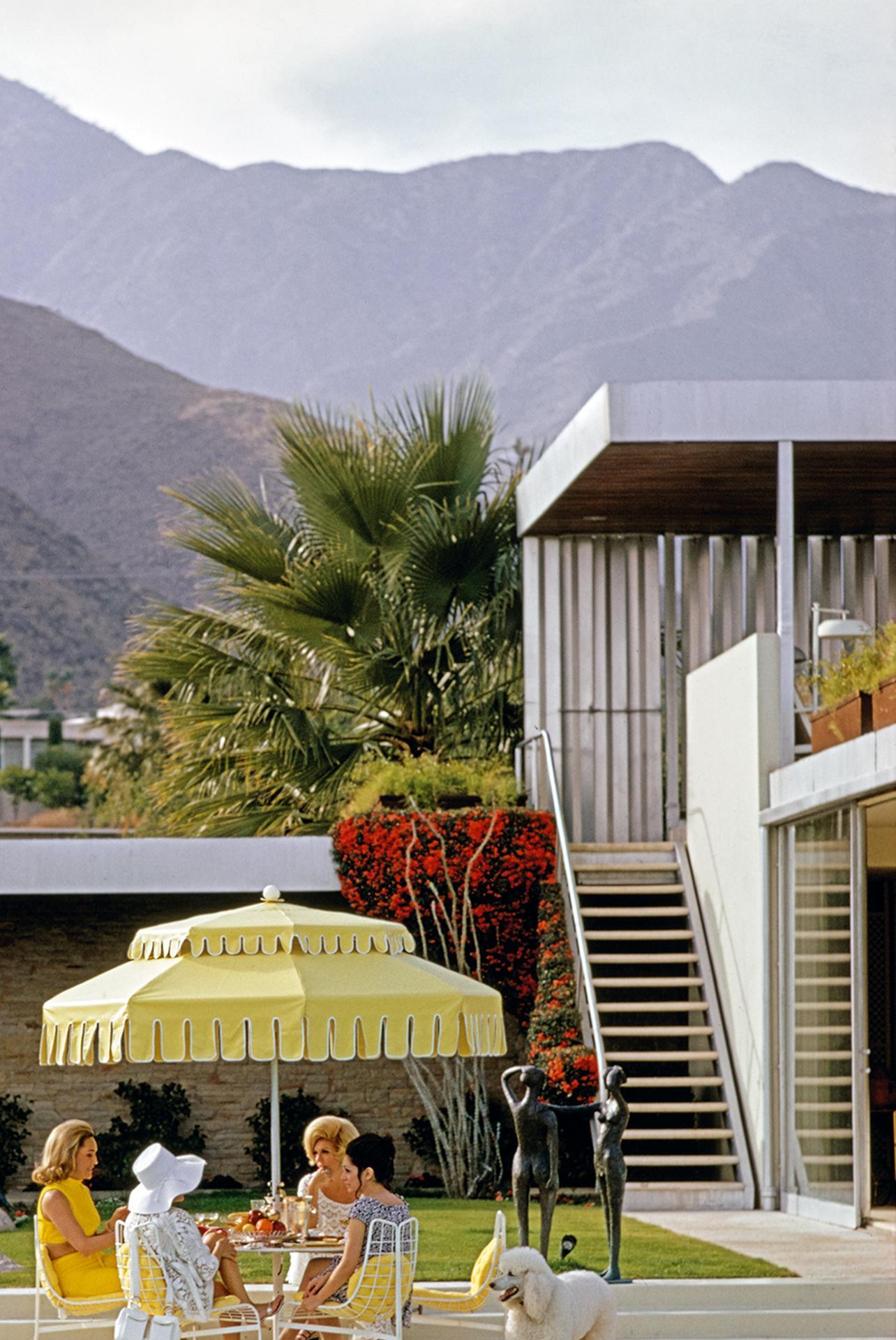 Dieses Porträtfoto von 1970, aufgenommen vom Society-Fotografen Slim Aarons, zeigt Nelda Linsk (links, in gelb), die Frau des Kunsthändlers Joseph Linsk, mit Gästen am Pool des Linsk-Hauses in Palm Springs, Januar 1970. In der Mitte, links, ist die