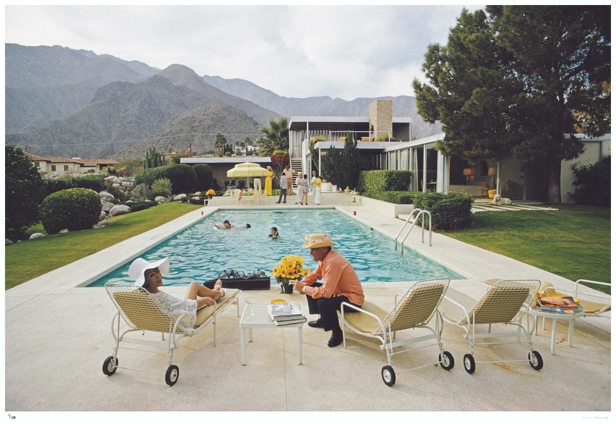 Poolside Interruptions 1970 - Slim Aarons Estate Stamped

Lita Baron talking with a guest at a poolside party at Nelda Linsk’s desert house in Palm Springs, California, January 1970. The house was designed by Richard Neutra for Edgar J.