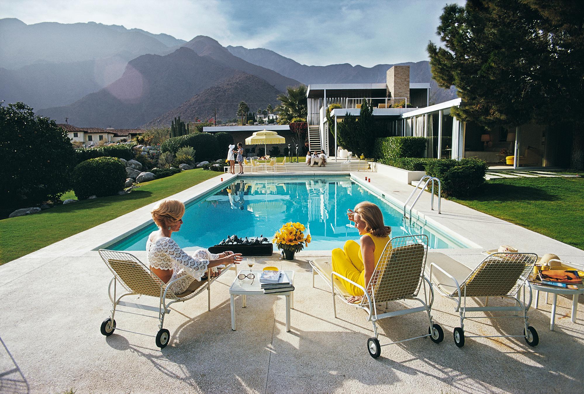 'Poolside Pairs' 1970 Slim Aarons Limited Estate Edition Print 

Former fashion model Helen Dzo Dzo Kaptur (in white lace) and Nelda Linsk (in yellow), wife of art dealer Joseph Linsk, at the Kaufmann Desert House in Palm Springs, California,
