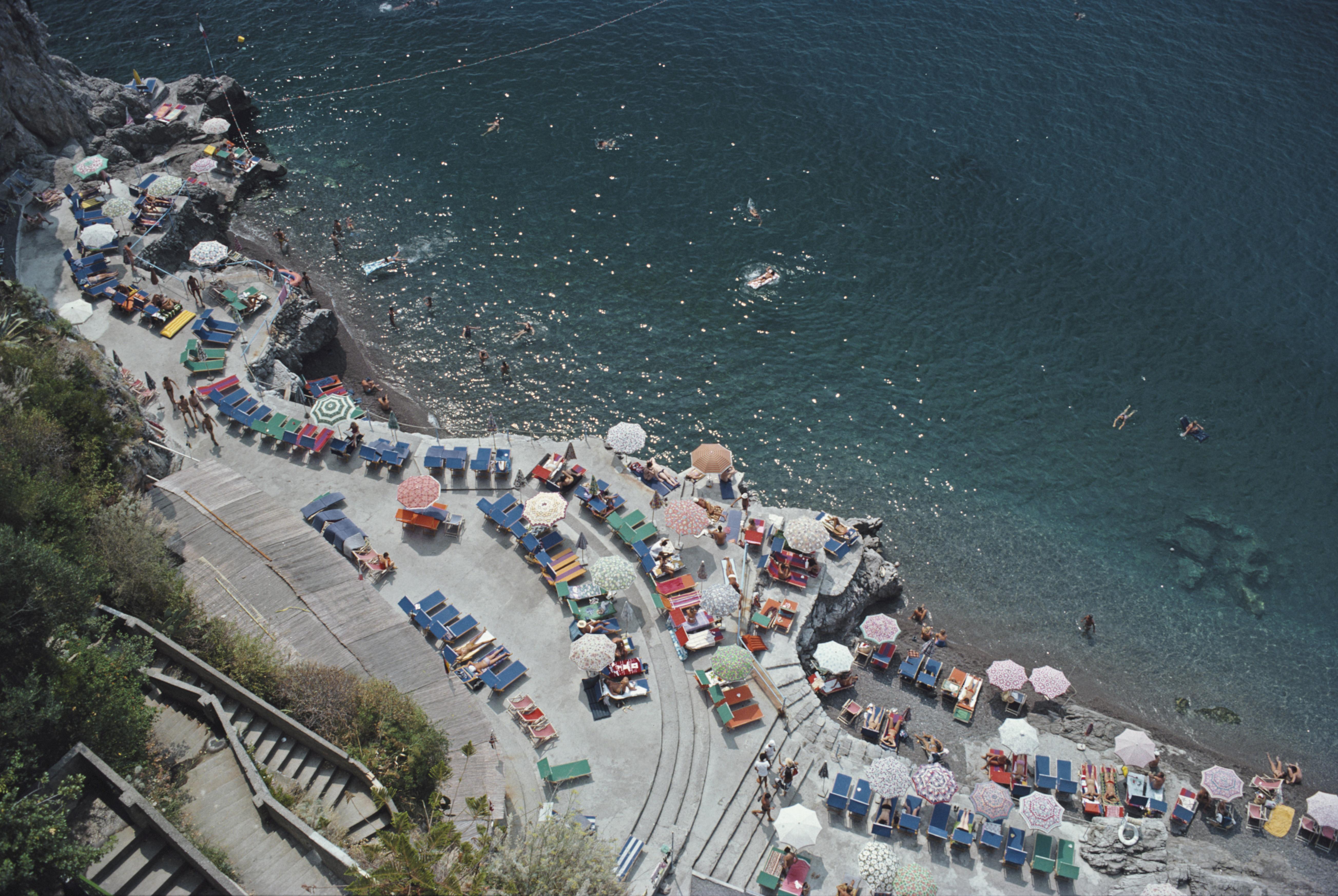 positano Beach' 1979 Slim Aarons Limitierte Nachlassausgabe Druck 

Blick von oben auf die Sonnenanbeter und Sonnenschirme am Strand von La Scogliera in Positano, Italien, 1979. 

Hergestellt aus der Originalfolie
Mitgeliefertes Echtheitszertifikat