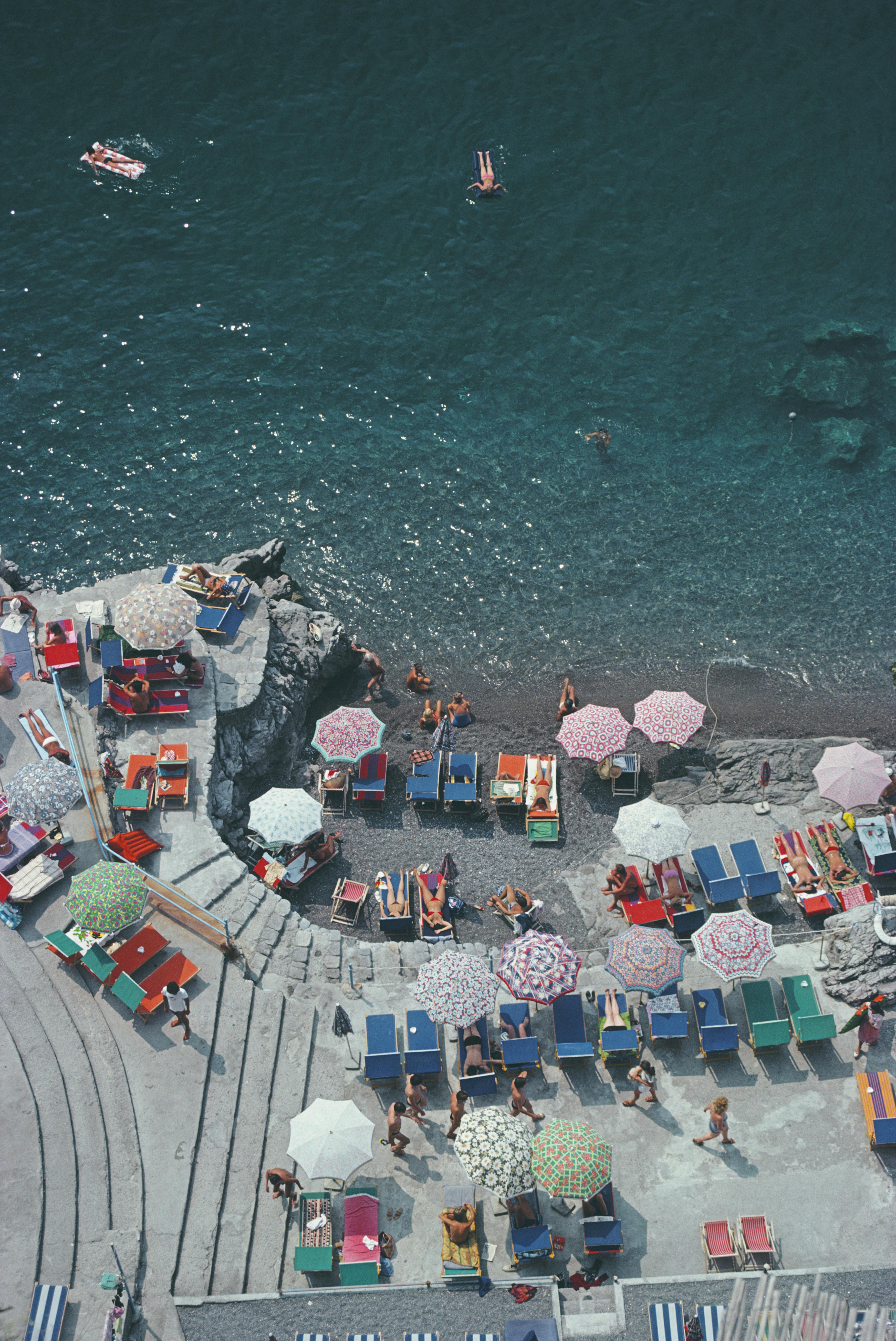 positano Beach' 1979 Slim Aarons Limitierte Nachlassausgabe Druck 

Blick von oben auf die Sonnenanbeter und Sonnenschirme am Strand von La Scogliera in Positano, Italien, 1979.

Hergestellt aus der Originalfolie
Mitgeliefertes Echtheitszertifikat