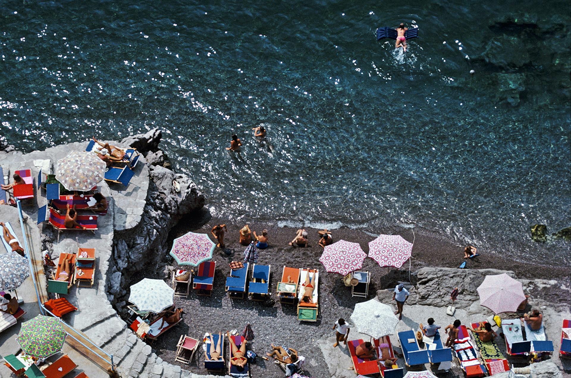 Cette photographie de paysage datant de la fin des années 1970, prise par le photographe mondain Slim Aarons, présente une vue en plongée des baigneurs et des parasols sur la plage de La Scogliera à Positano, en Italie.

Il s'agit d'une édition de