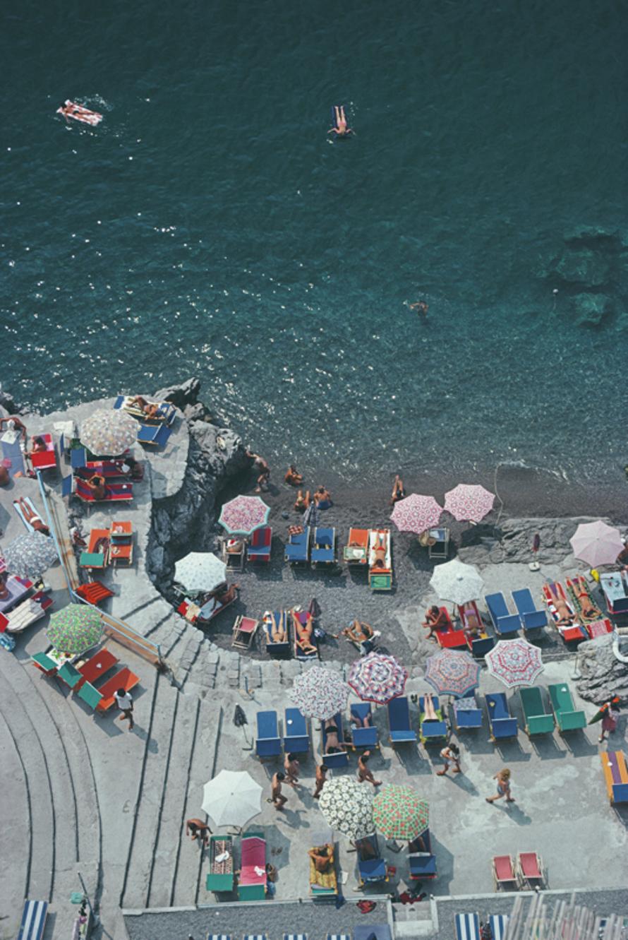 Positano Beach 
1979
by Slim Aarons

Slim Aarons Limited Estate Edition

Elevated view looking down on sunbathers and parasols on the beach at La Scogliera beach in Positano, Italy, 1979

unframed
c type print
printed 2023
24 x 20"  - paper