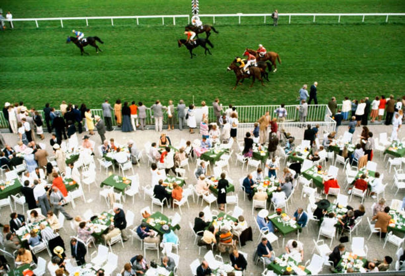 Racing At Baden Baden 
1978
by Slim Aarons

Slim Aarons Limited Estate Edition

Spectators dine in the open air as the horses go by at Baden Baden racecourse, Germany, September 1978.

unframed
c type print
printed 2023
16×20 inches - paper
