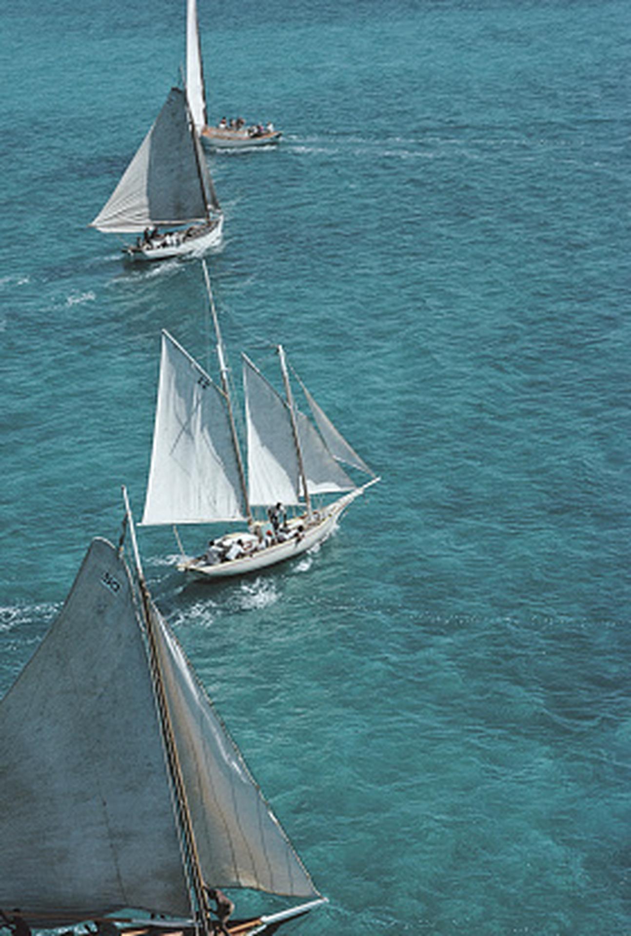 Dieses Porträtfoto des Gesellschaftsfotografen Slim Aarons aus den späten 1960er Jahren zeigt ein Besatzungsmitglied, das sich um die Takelage einer Yacht in Lyford Cay auf den Bahamas kümmert.

Dies ist eine nachlassgestempelte und handnummerierte