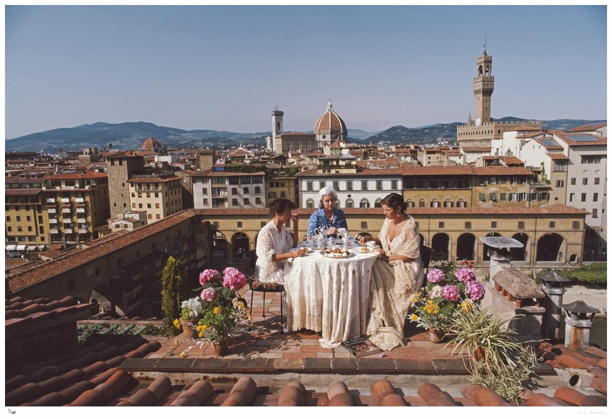 Santa And Serena Antonelli 1983 - Slim Aarons

Santa and Serena Antonelli and a guest dining al fresco on the terrace of their home above Via Giucciardini, in Florence, Italy, 1983. Rising beyond are the dome of the Basilica di Santa Maria del Fiore