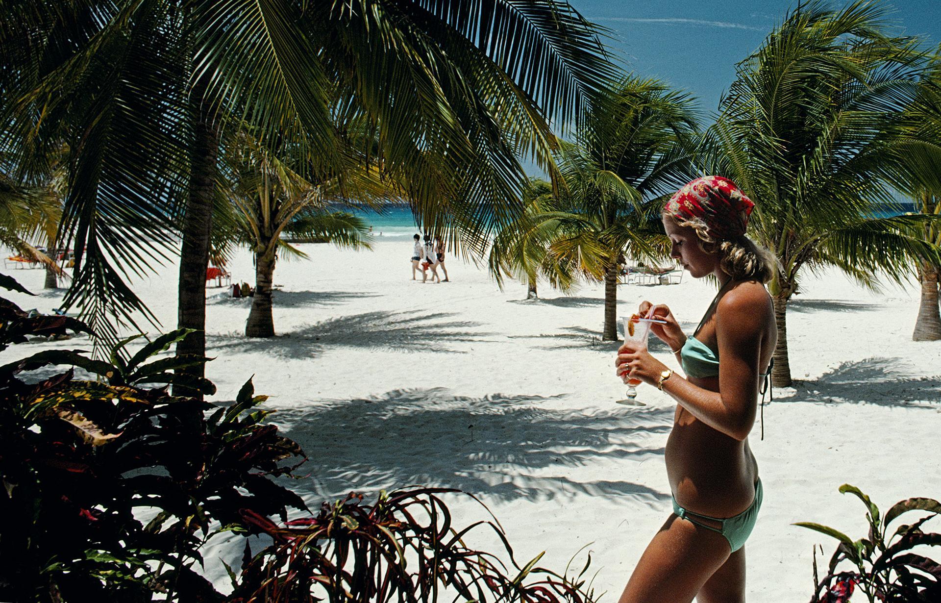 Questo ritratto della metà degli anni '70, scattato dal fotografo di società Slim Aarons, ritrae Sarah Williams mentre si gode un cocktail sulla spiaggia dell'Hilton Hotel, a Needhams Point, Barbados, nell'aprile del 1976.

Si tratta di un'edizione