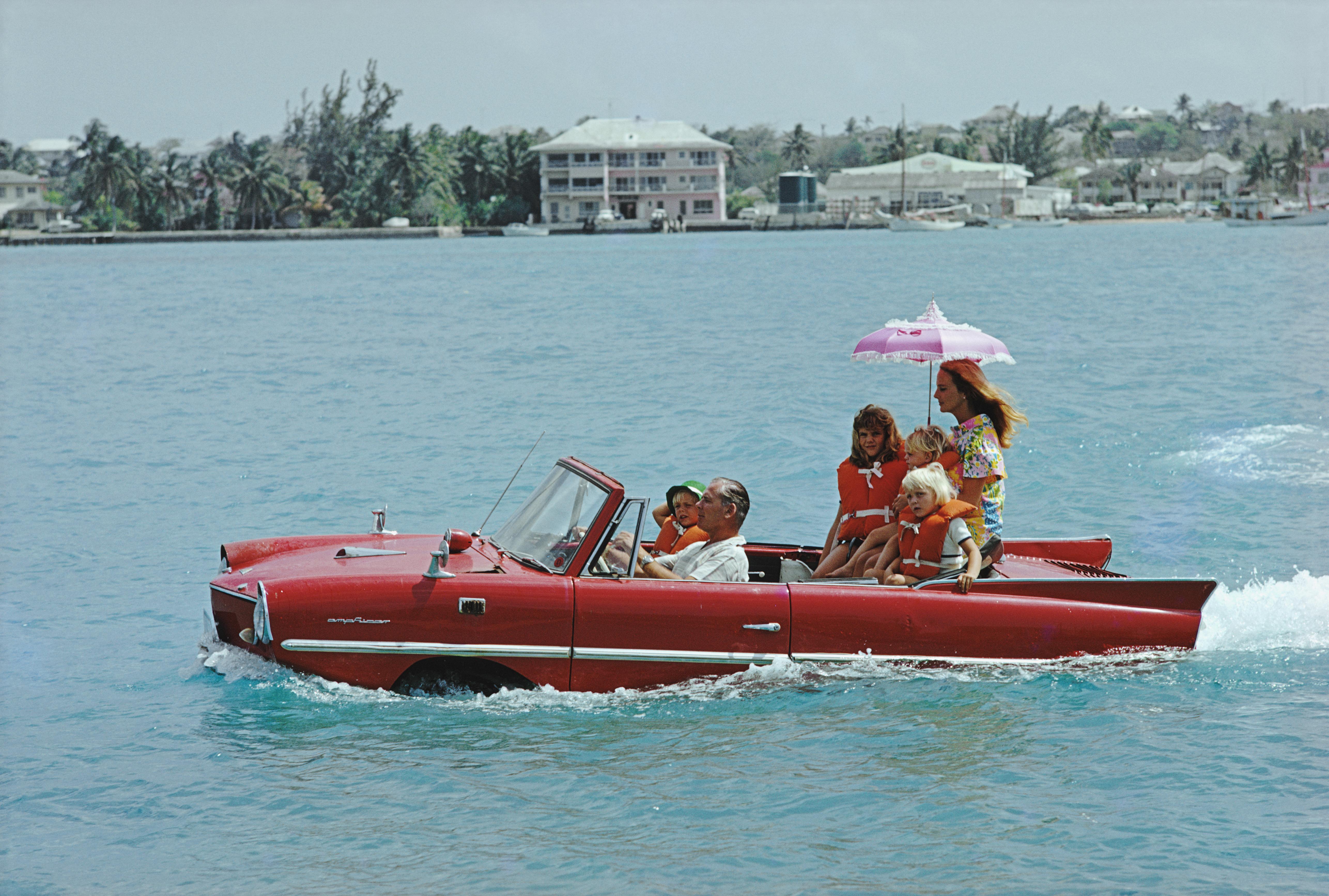 'Sea Drive' 1969 Slim Aarons Limited Estate Edition Print 

Film producer Kevin McClory takes his wife Bobo Sigrist and their family for a drive in an 'Amphicar' across the harbour at Nassau. The children are Bianca Juarez (Bobo's daughter from
