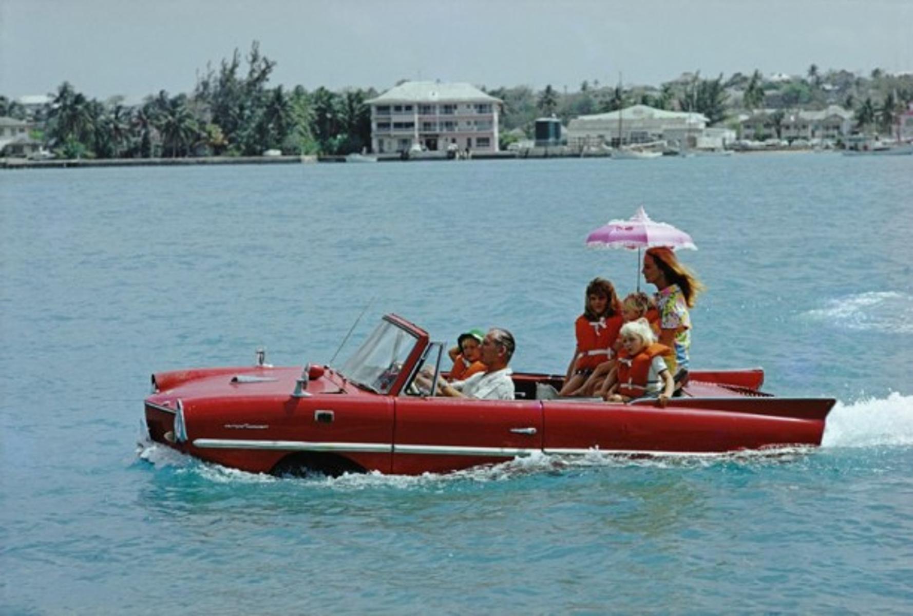Sea Drive
1967
by Slim Aarons

printed 2023
Slim Aarons Limited Estate Edition

Film producer Kevin McClory takes his wife Bobo Sigrist and their family for a drive in an ‘Amphicar’ across the harbour at Nassau. The children are Bianca Juarez