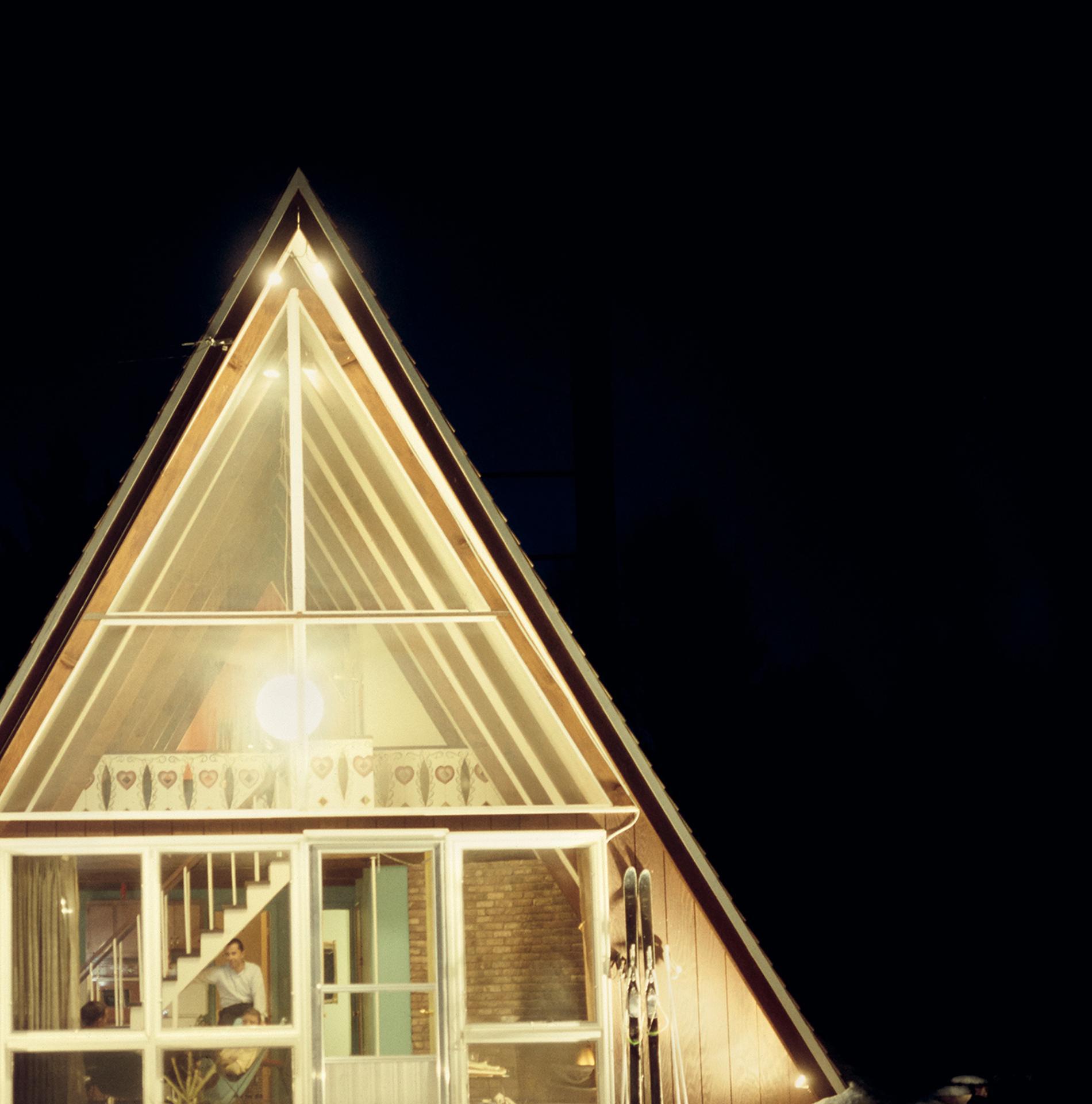 Das dreieckige Skaal House mit Glasfassade, nachts beleuchtet, im Skigebiet Stowe Mountain in Stowe, Vermont, 1962. Ein Paar Skier lehnte an der Wand neben der Tür. 

Slim Aarons Estate Edition, inklusive Echtheitszertifikat
Nummeriert und