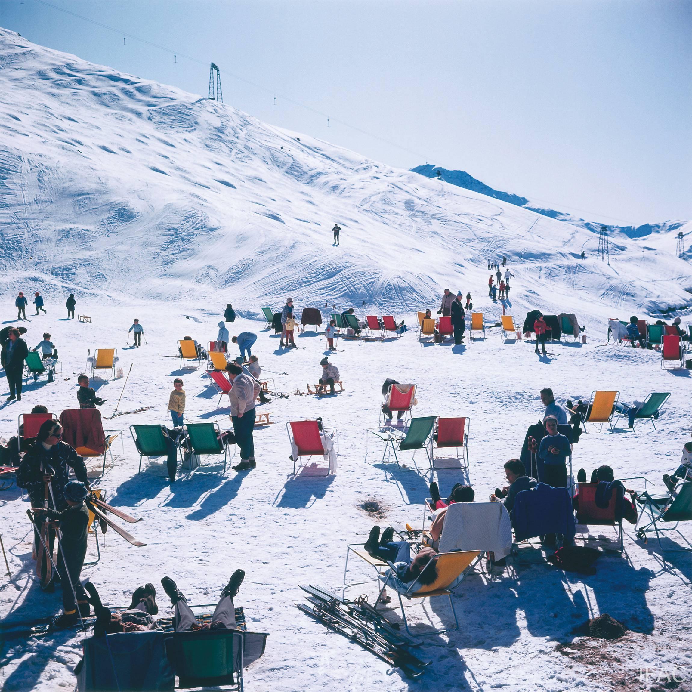 Skifahrer in Verbier, 1964 
Archivierungs-Pigmentdruck 
Nachlassgestempelte und handnummerierte Auflage von 150 Stück mit Echtheitszertifikat des Nachlasses.  

Skifahrer entspannen sich in Liegestühlen auf den Pisten von Verbier in der Schweiz,
