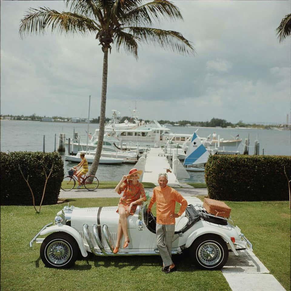 All Mine, 1968 by Slim Aarons, Printed Later.
Jim Kimberly and his wife, with his white sports car and white boats moored on Lake Worth. A Palm Beach socialite, he acts as Honorary 
Consul of Jordan.

Estate Stamped Edition of 150 
With a