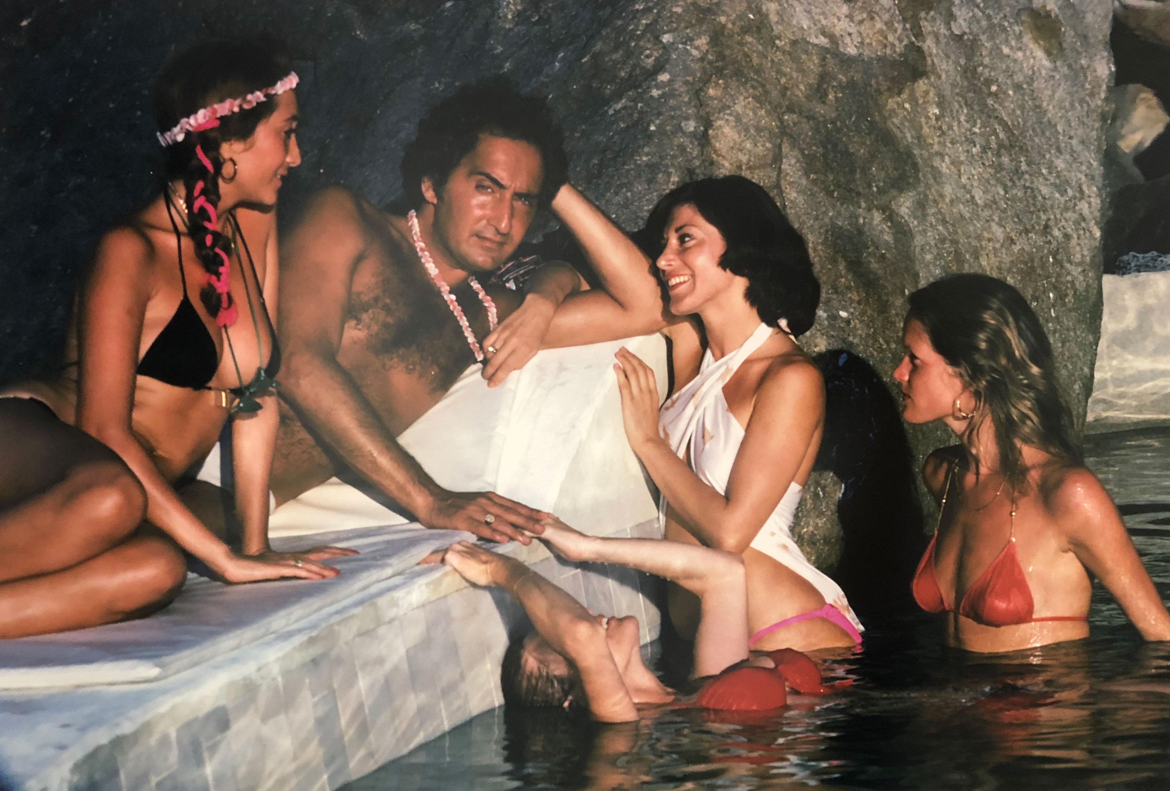 Au bord de la piscine à Acapulco, 1978
C Imprimer
24 x 20 pouces
Tirage de 150 exemplaires, numérotés à la main, avec certificat d'authenticité. 

Un homme bronzé entouré de jeunes femmes en bikini au bord de la piscine de la villa de Warren Avis à