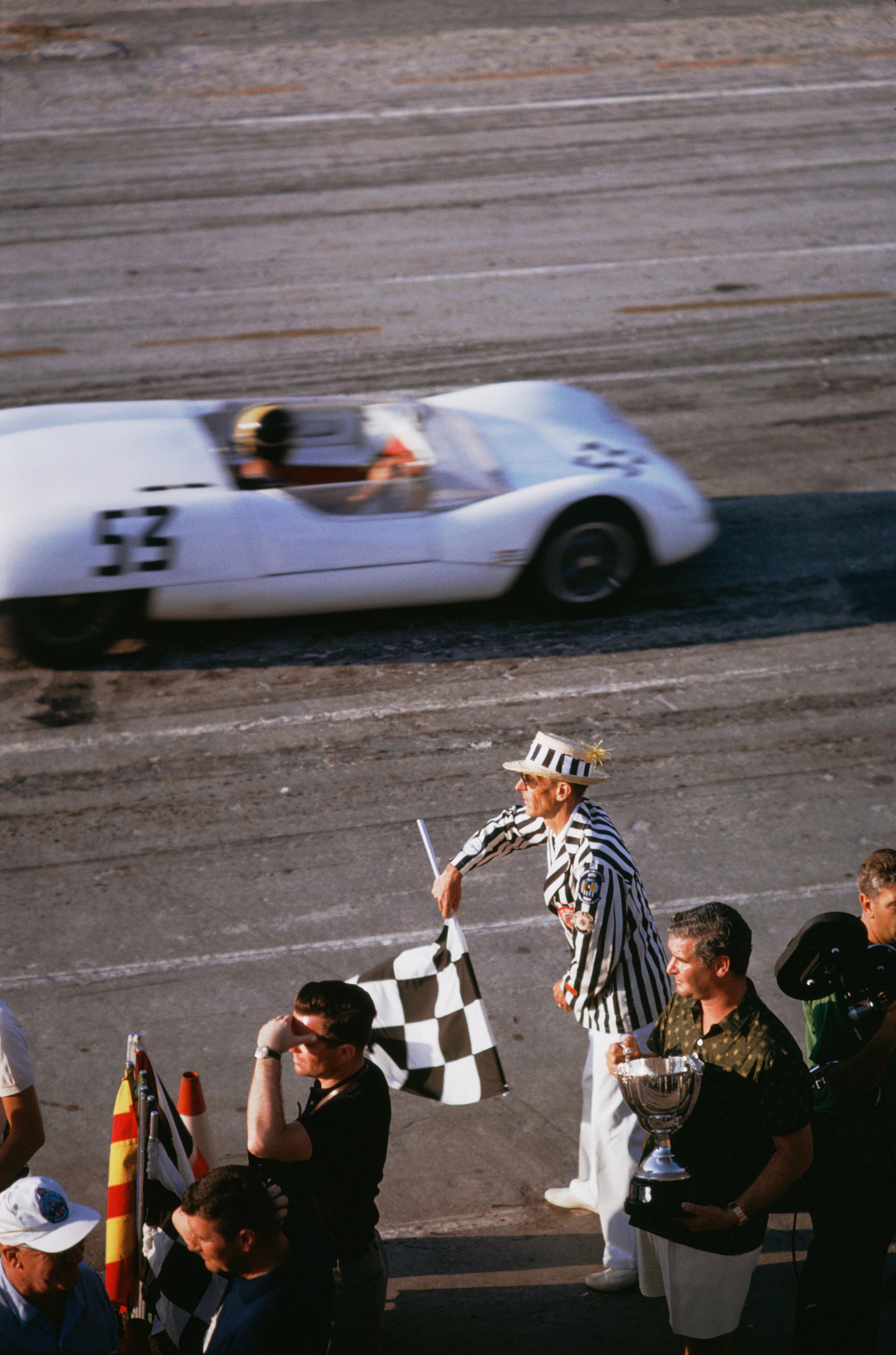 'Checkered Flag' 1963 Slim Aarons Limited Estate Edition
The checkered flag signals the end of the race during the 1963 Nassau Speed Week. 

Slim Aarons Chromogenic C print 
Printed Later 
Slim Aarons Estate Edition 
Produced utilising the only