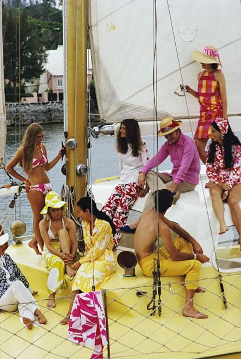 Slim Aarons
Equipaggio colorato, 1970
Stampa cromogenica Lambda
Edizione stampata e numerata a mano di 150 esemplari con certificato di autenticità. 

Un gruppo di vacanzieri vestiti in modo colorato su uno yacht, Bermuda, giugno 1970.
 
Slim Aarons