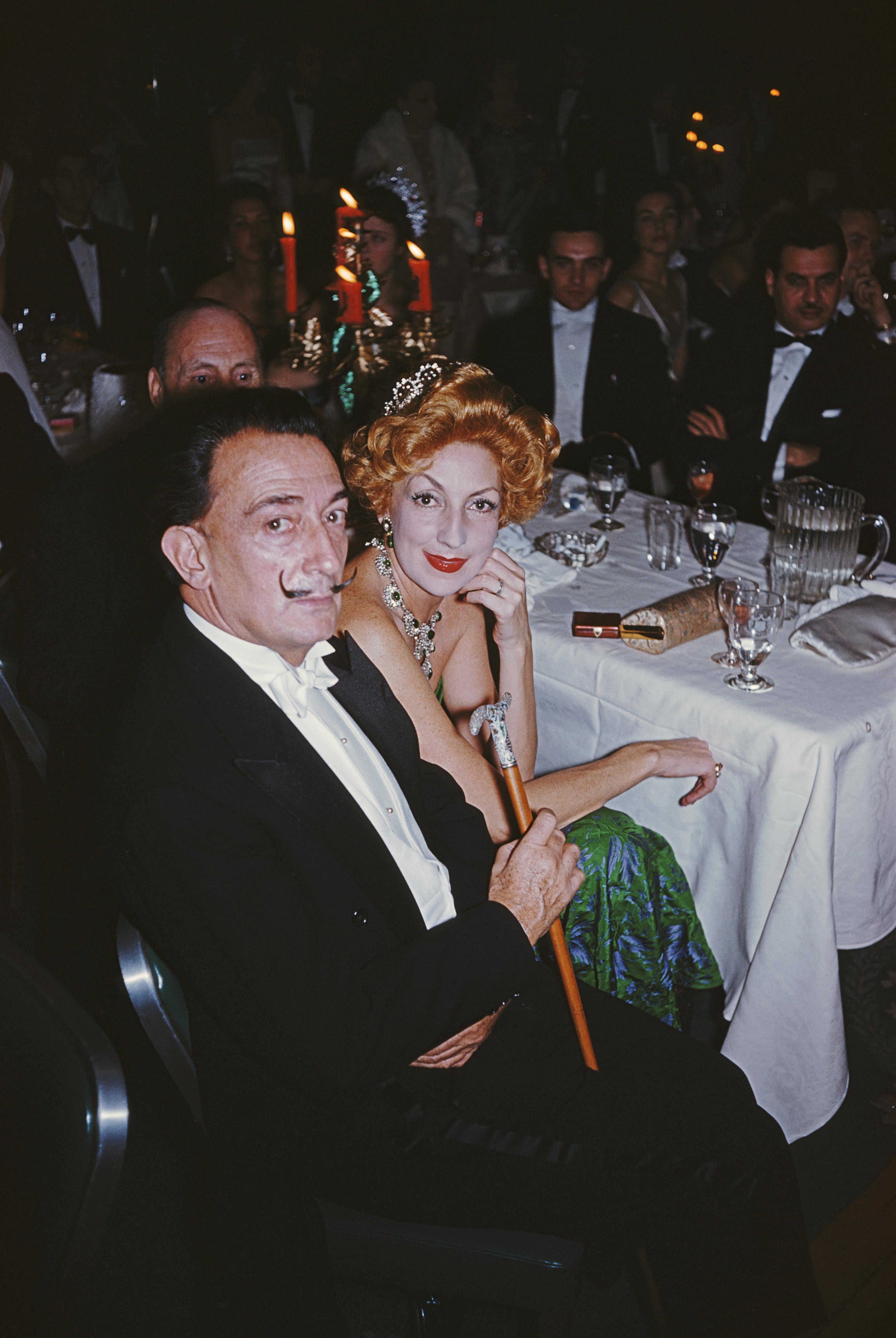 Slim Aarons
Dali's Party
1959
Chromogenic Lambda print
Estate stamped and hand numbered edition of 150 with certificate of authenticity. 

circa 1959: Surrealist painter Salvador Dali (1904 - 1989) with a red-haired woman at a ball in New York. A