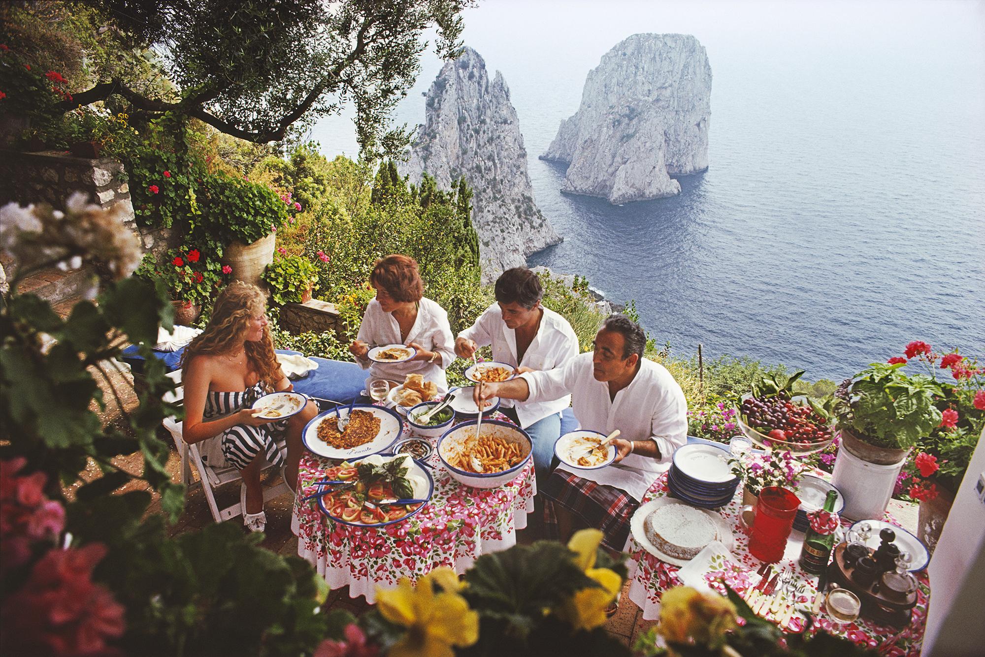 L'artiste et actrice italienne Domiziana Giordano, l'auteur italienne Francesca Sanvitale (1928 - 2011), Dino Trappetti et Umberto Terrelli dînant al fresco sur une terrasse surplombant les eaux au large de la côte de l'île de Capri, en Italie, en