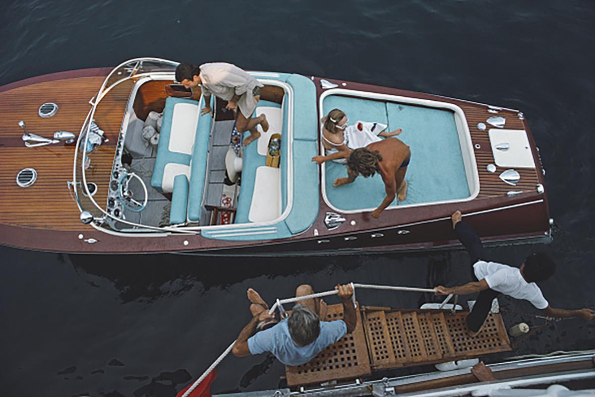 Slim Aarons Estate Stamped Edition 
Begrenzt auf 150 Exemplare 

Freunde besteigen ein Riva-Boot in Monte Carlo, Monaco, 1975. (Foto: Slim Aarons)

Dieses Foto verkörpert den Reisestil und den Glamour der Reichen und Berühmten dieser Zeit, der von