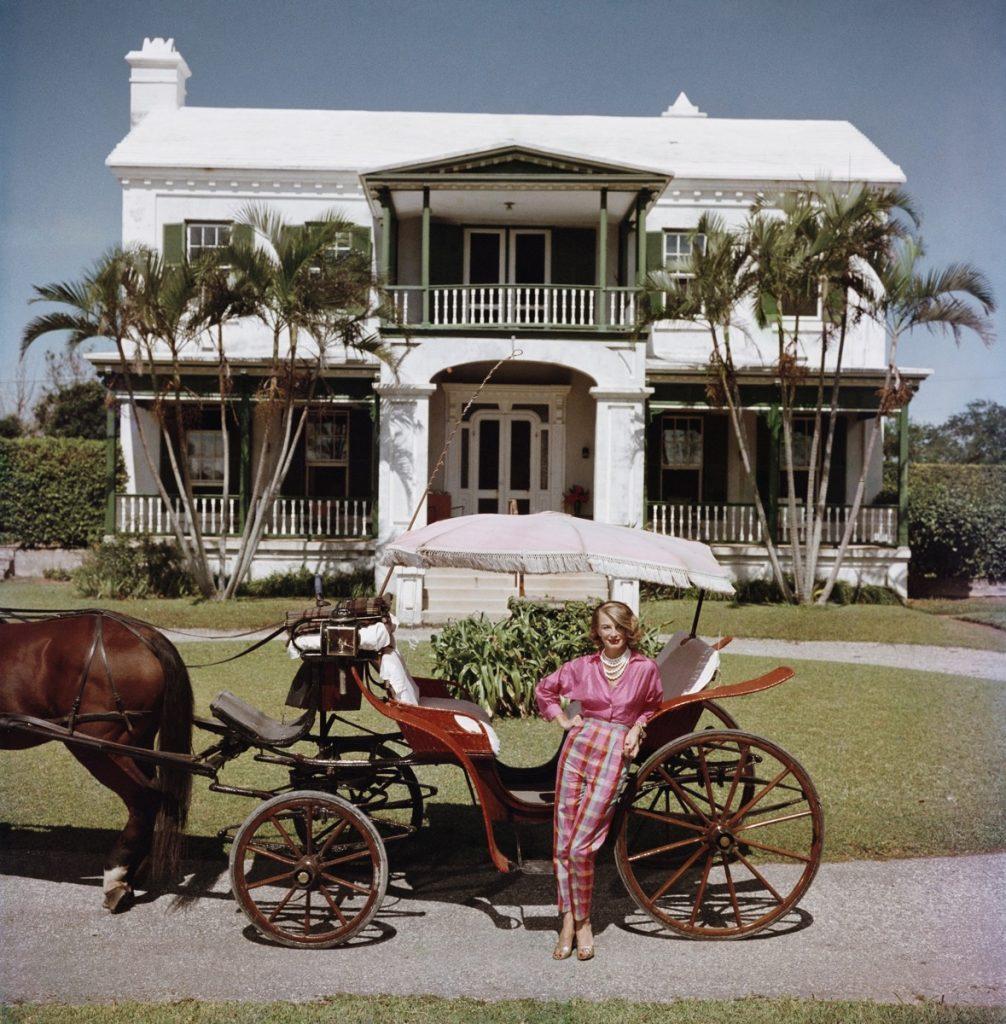Slim Aarons - Bermudan Hostess - Estate Stamped Edition 
Limited to 150 only 
Polly Trott Hornburg in front of her father’s typical Bermudian house. She is wearing her own design of Thaibok slacks and shirt for a ride in an open carriage, Bermuda,