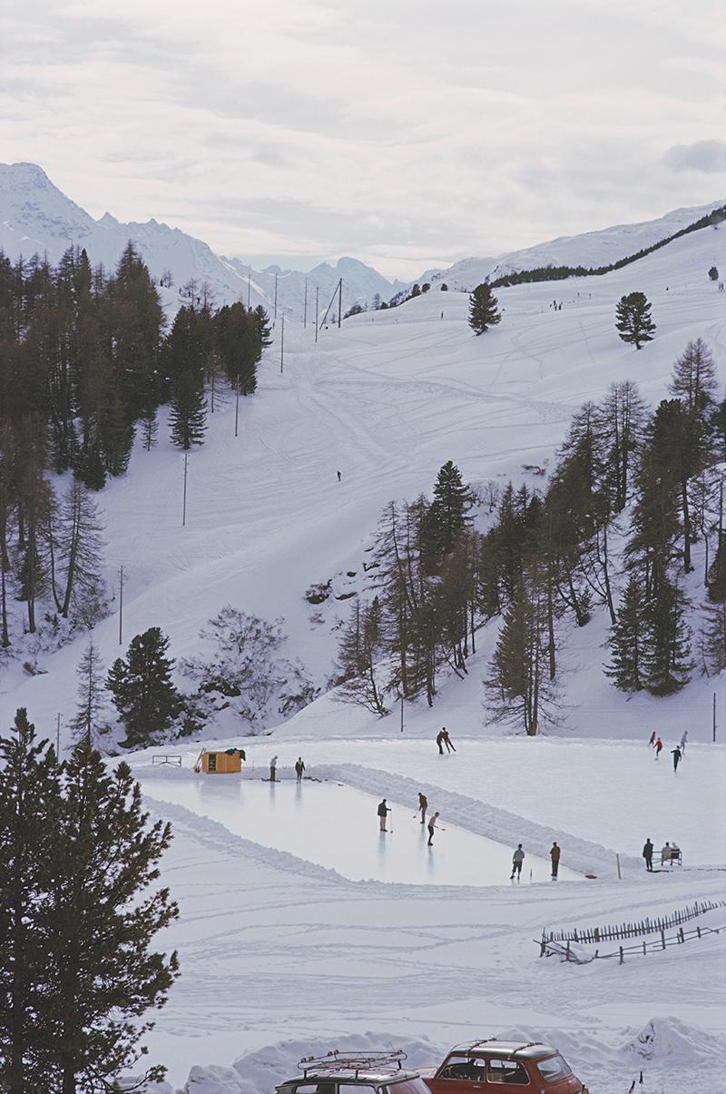 Slim Aarons Estate Stamped Edition 
Begrenzt auf 150 Exemplare 

Eisstockschützen auf einer Eislaufbahn in St. Moritz, Schweiz, März 1963 
(Foto: Slim Aarons)

Dieses Foto verkörpert den Reisestil und den Glamour der Reichen und Berühmten dieser