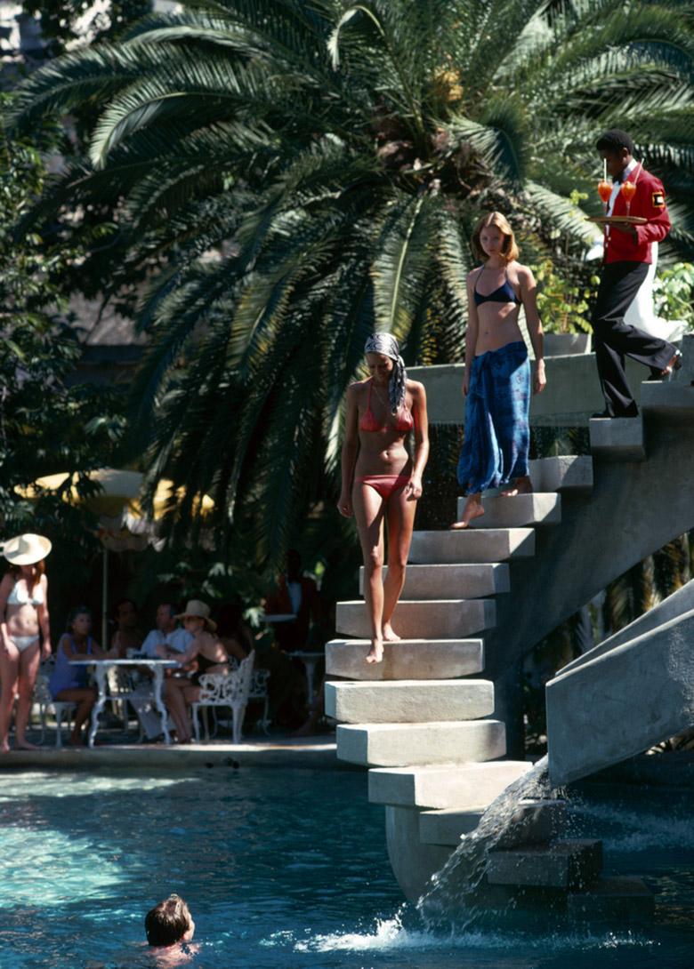 Slim Aarons Estate Stamped Edition 
Begrenzt auf 150 Exemplare 

Badegäste gehen die Stufen zum Schwimmbad in der Habitation Leclerc, Haiti, Januar 1975. 

Ihnen folgt ein Kellner mit Cocktails. (Foto: Slim Aarons)

Dieses Foto verkörpert den