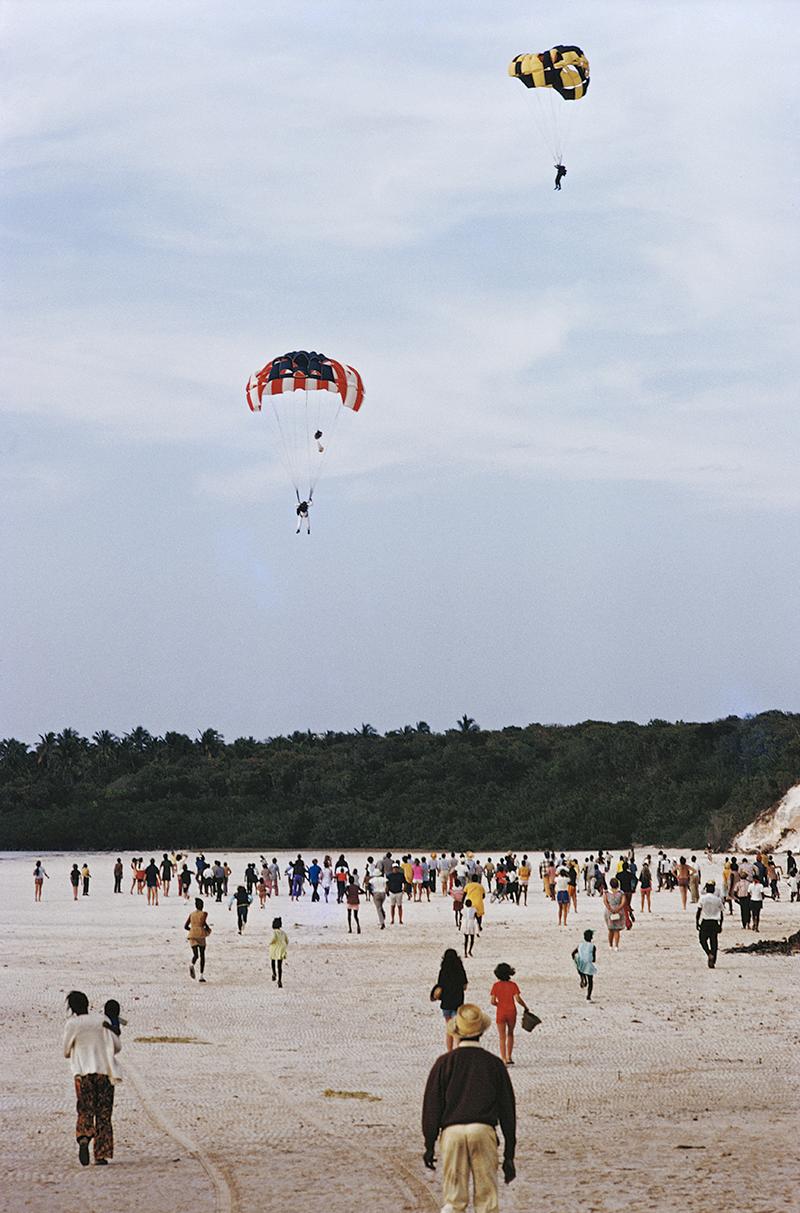 Slim Aarons Estate Stamped Edition 
Limited to 150 only 

Parachutists landing on the beach at Harbour Isle in the Bahamas, March 1973. (Photo by Slim Aarons)

This photograph epitomises the travel style and glamour of the period's wealthy and