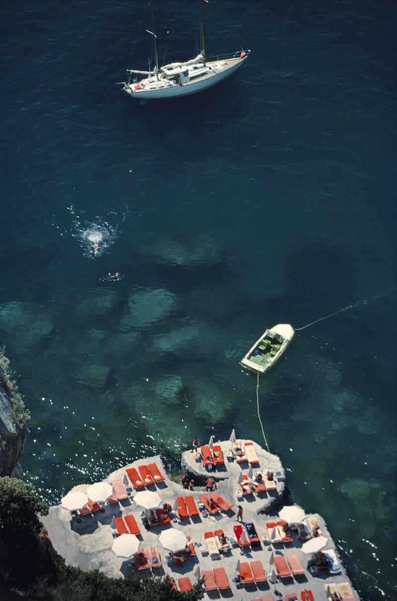Slim Aarons - Hotel IL San Pietro - Nachlassgestempelte Ausgabe 
Begrenzt auf 150 Exemplare 
Gäste im Hotel Il San Pietro in Positano, Italien, August 1979 (Foto von Slim Aarons). 


Dieses Foto verkörpert den Reisestil und den Glamour der Reichen