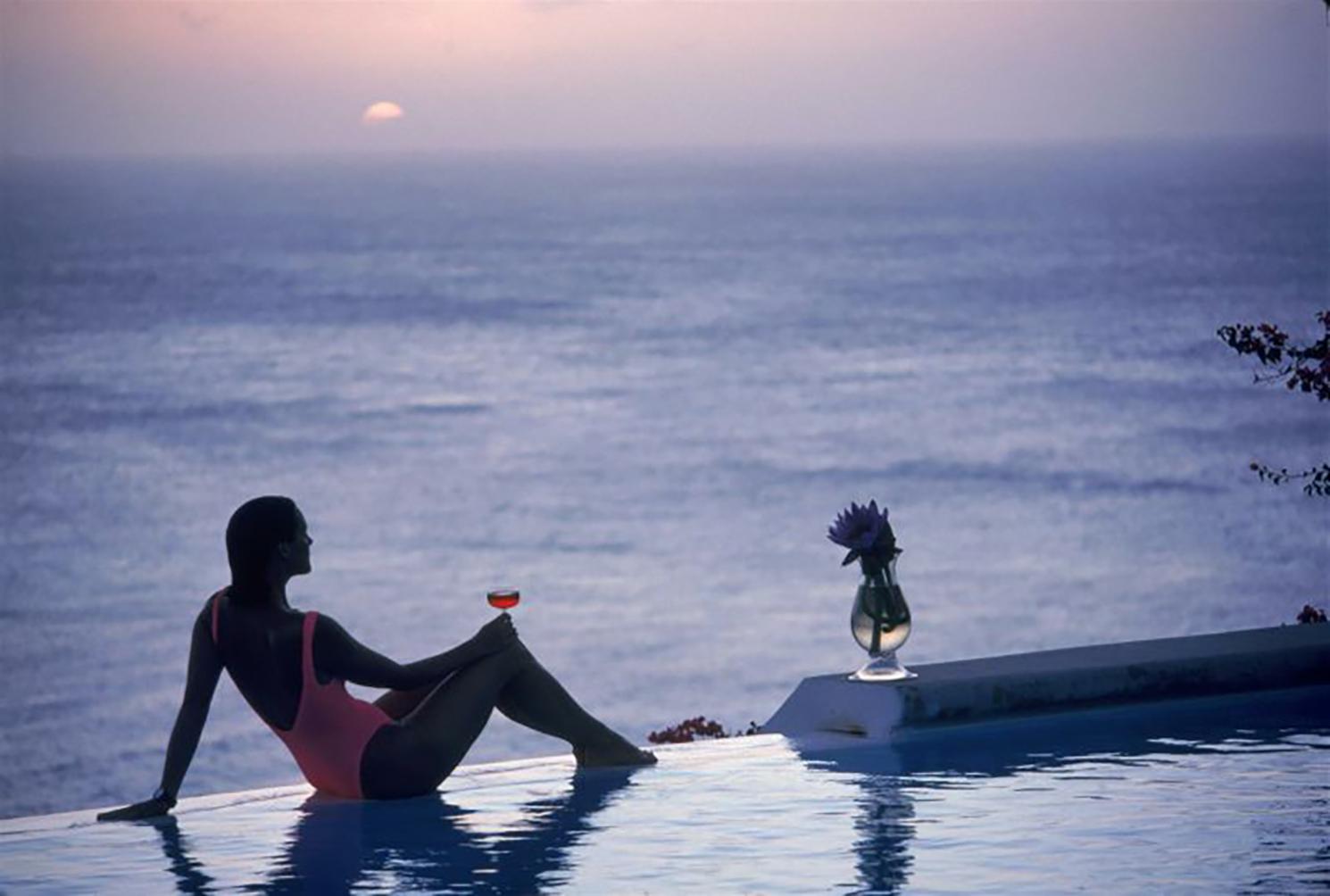 Slim Aarons - Mustique Tranquility - Édition estampillée par l'État 
Limité à 150 seulement 
Meg O'Neill, rédactrice du magazine Town and Country, se détend au bord de la piscine à débordement de la maison de Colin Tennant sur l'île antillaise de