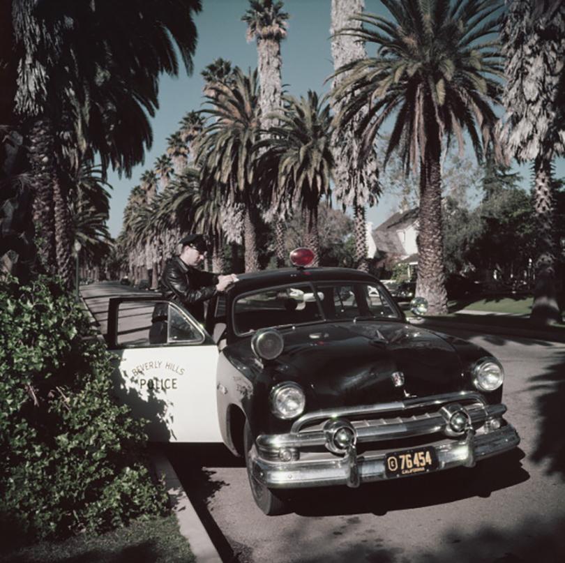 Slim Aarons Estate Stamped Edition 
Limited to 150 only 

Beverly Hills police patrolman Lee R. Hathaway leaning on the roof of his car to write a report, Bedford Drive, Beverly Hills, California, 1952 (Photo by Slim Aarons). 


This photograph