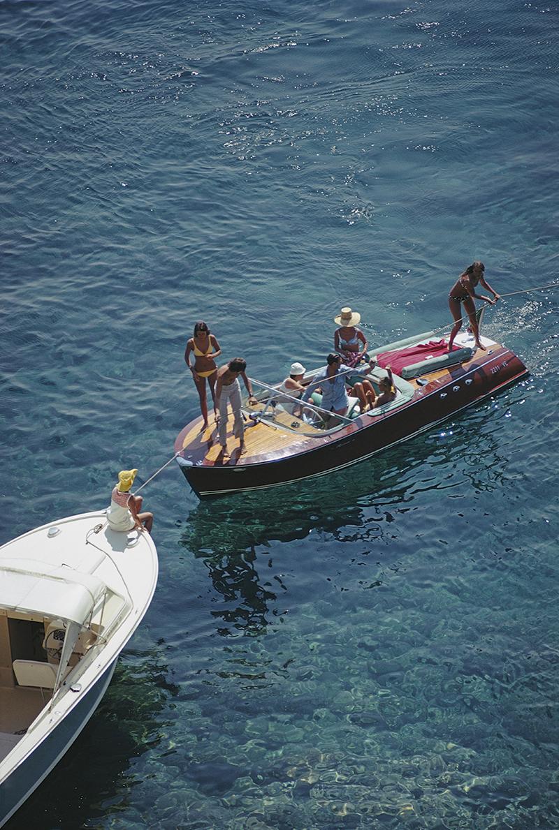 Slim Aarons Estate Stamped Edition 
Limited to 150 only 

Boating in Porto Ercole, Italy, August 1969 (Photo by Slim Aarons)

This photograph epitomises the travel style and glamour of the period's wealthy and famous, beautifully documented by