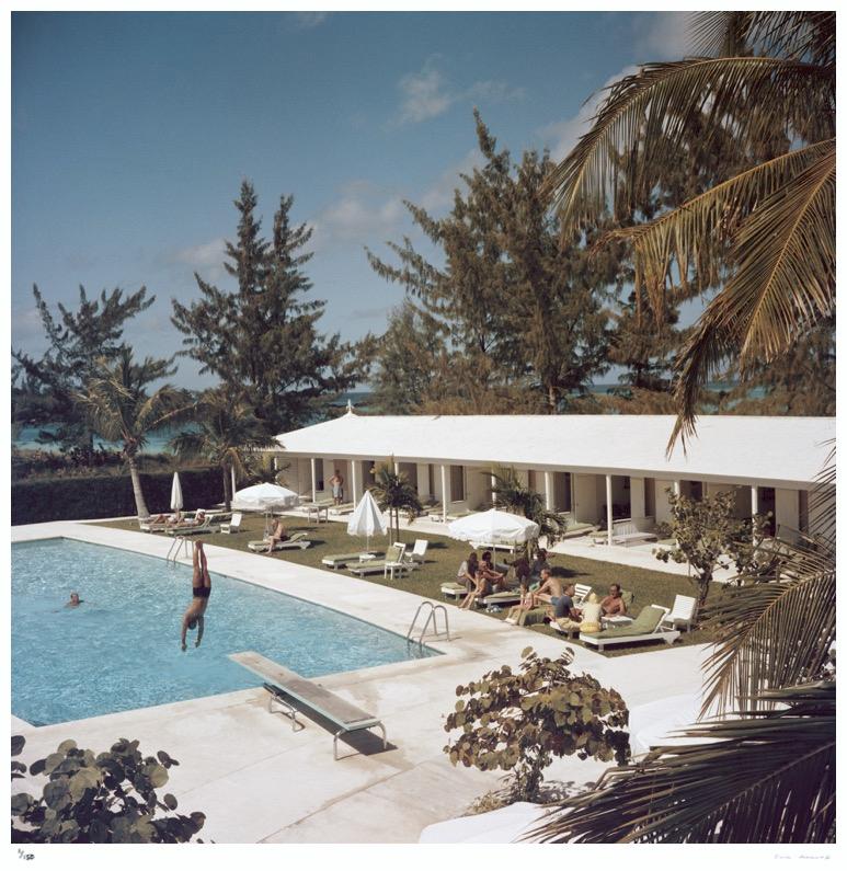 Slim Aarons Estate Edition -  Taking The Plunge 

Limited Edition Estate Stamped Print (edition size 1/150).

A swimming pool at the Lyford Cay Club at Lyford Cay on New Providence Island in the Bahamas, 1962. The club building was designed by