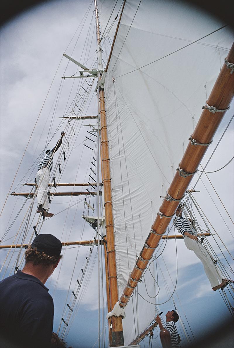 Slim Aarons Estate Stamped Edition 
Limited to 150 only 

Crew members tend to the rigging while sailing in Lyford Cay, Bahamas, April 1966. (Photo by Slim Aarons)

This photograph epitomises the travel style and glamour of the period's wealthy and