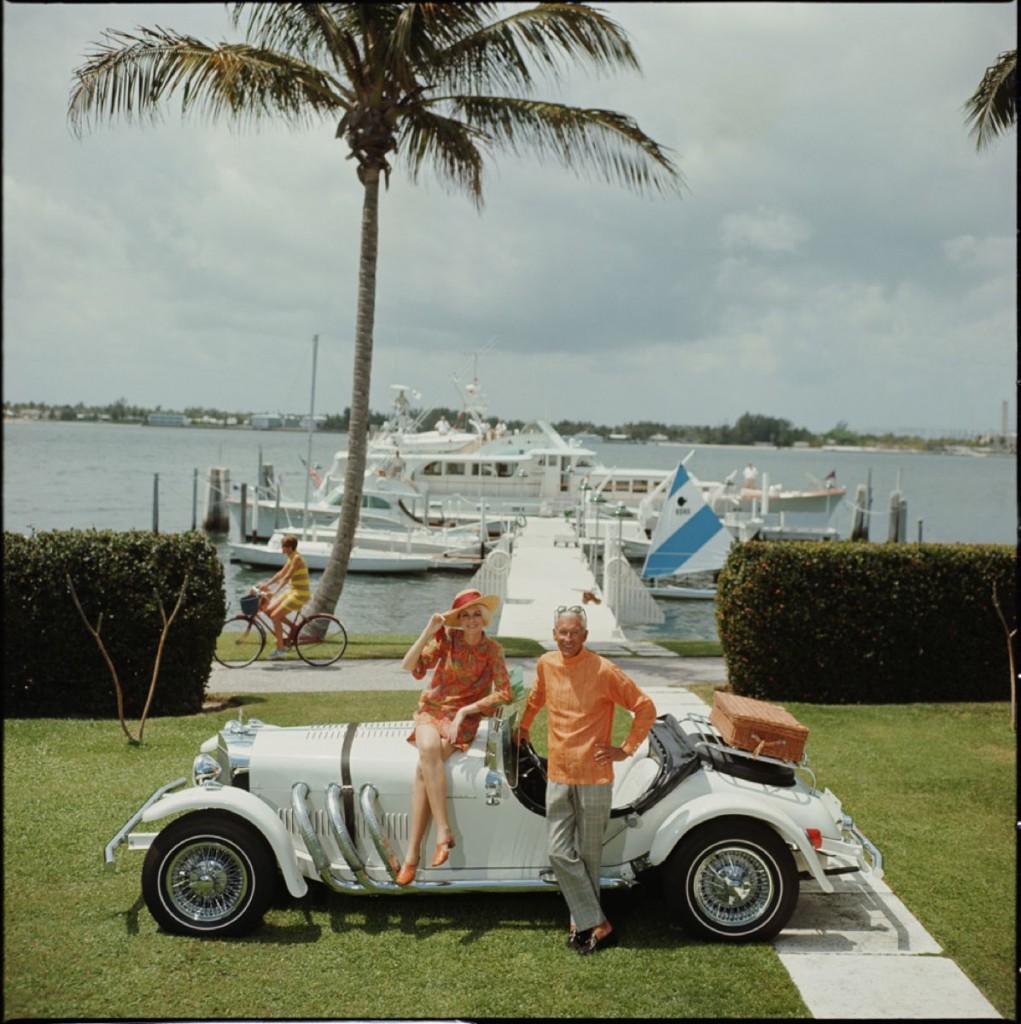Slim Aarons Estate Druck - All Mine - Übergröße

Jim Kimberly und seine Frau mit seinem weißen Sportwagen und weißen Booten, die am Lake Worth vertäut sind. Der aus Palm Beach stammende Prominente fungiert als Honorarkonsul von Jordanien. Original