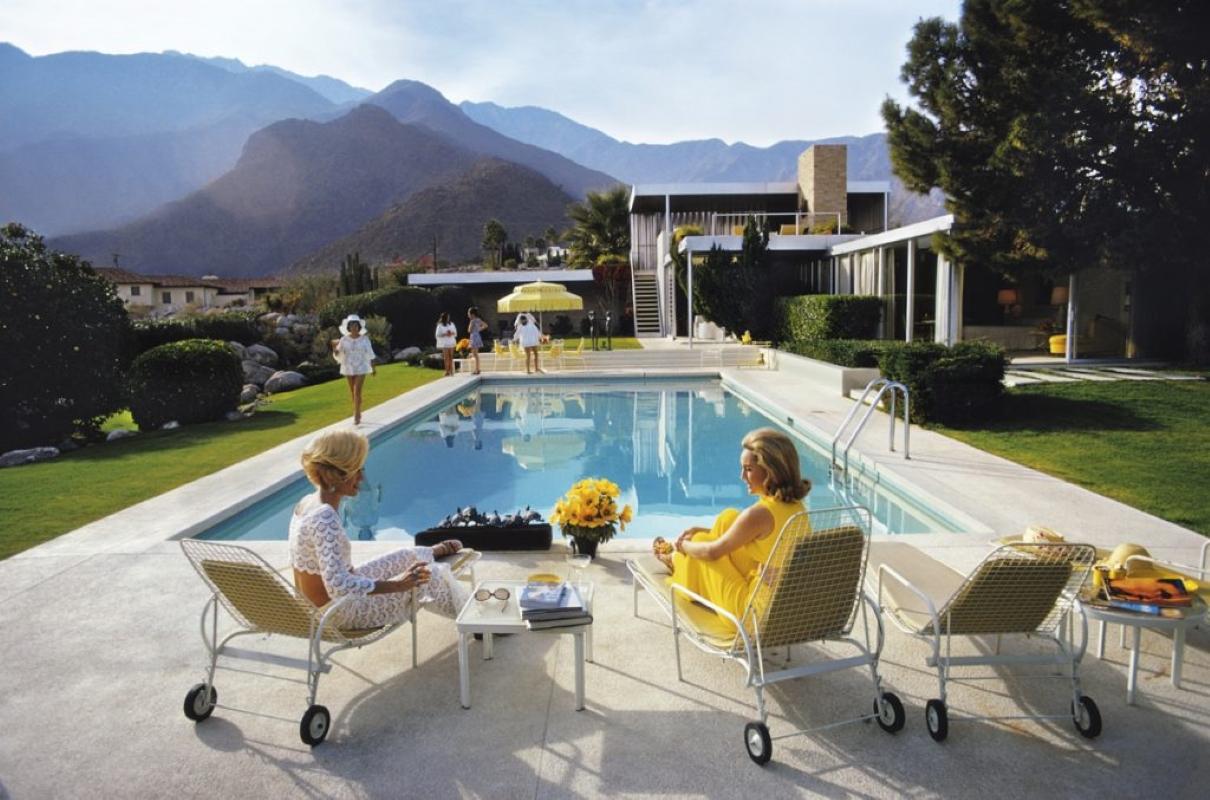 Slim Aarons Estate Print - Poolside Glamour - Oversize

A desert house in Palm Springs designed by Richard Neutra for Edgar J. Kaufmann. Lita Baron approaches on the right Nelda Linsk, wife of art dealer Joseph Linsk who is talking to a friend,