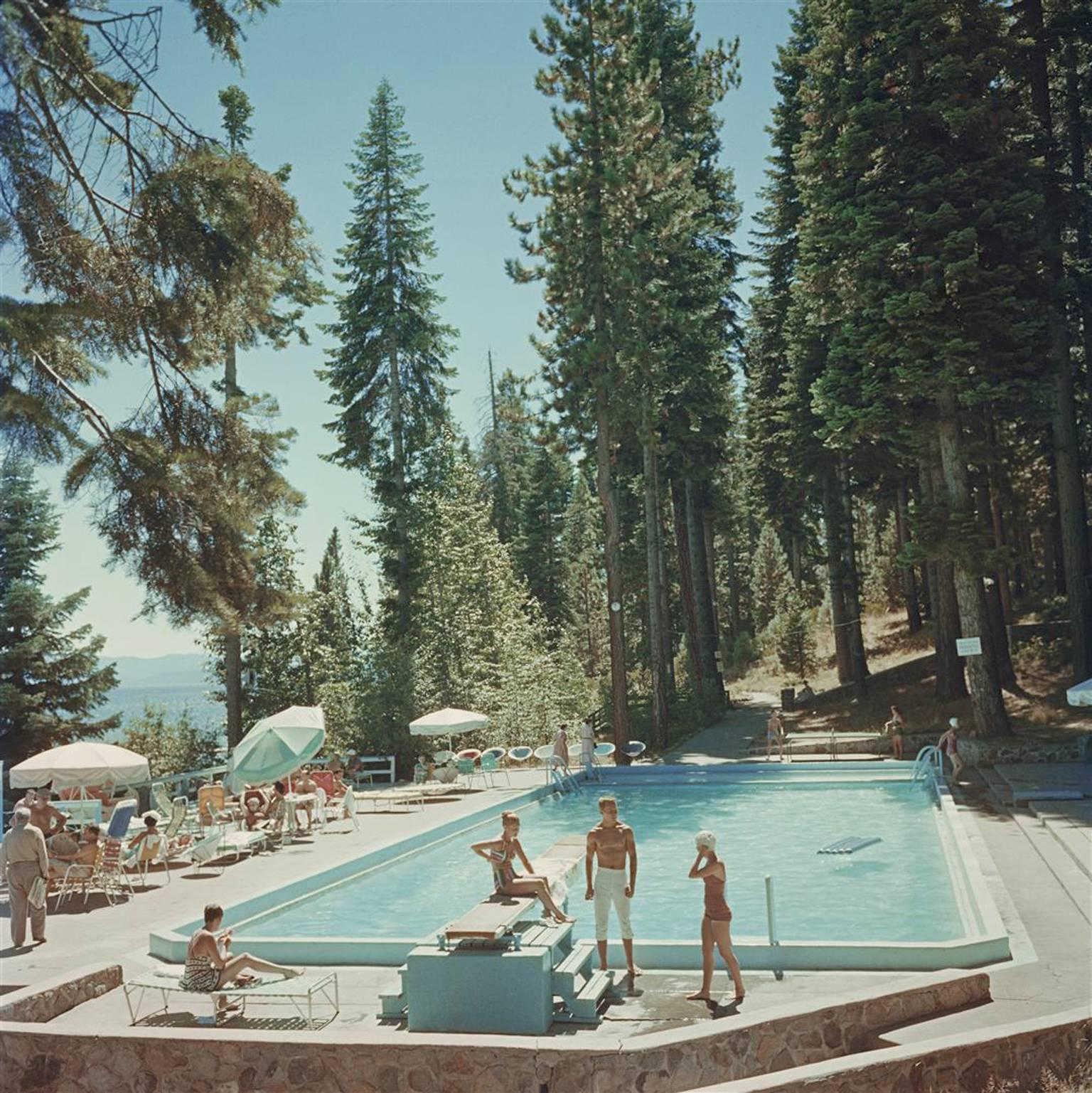 Bathers by a pool on the shore of Lake Tahoe, California, 1959. 
Fashionable bathers relax underneath parasols and on sun loungers beside the swimming pool, overlooking Lake Tahoe on a beautiful sunny day.

Typically 'Slim Beach' this photograph