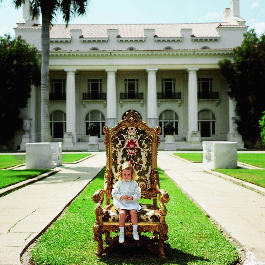 Slim Aarons - Family Chair - Estate Stamped

Elizabeth Matthews, descendant of H M Flagler co-founder of Palm Beach, sits in her great-grandfather’s favourite chair in front of the family mansion now the Flagler Museum, Palm Beach, April 1968.