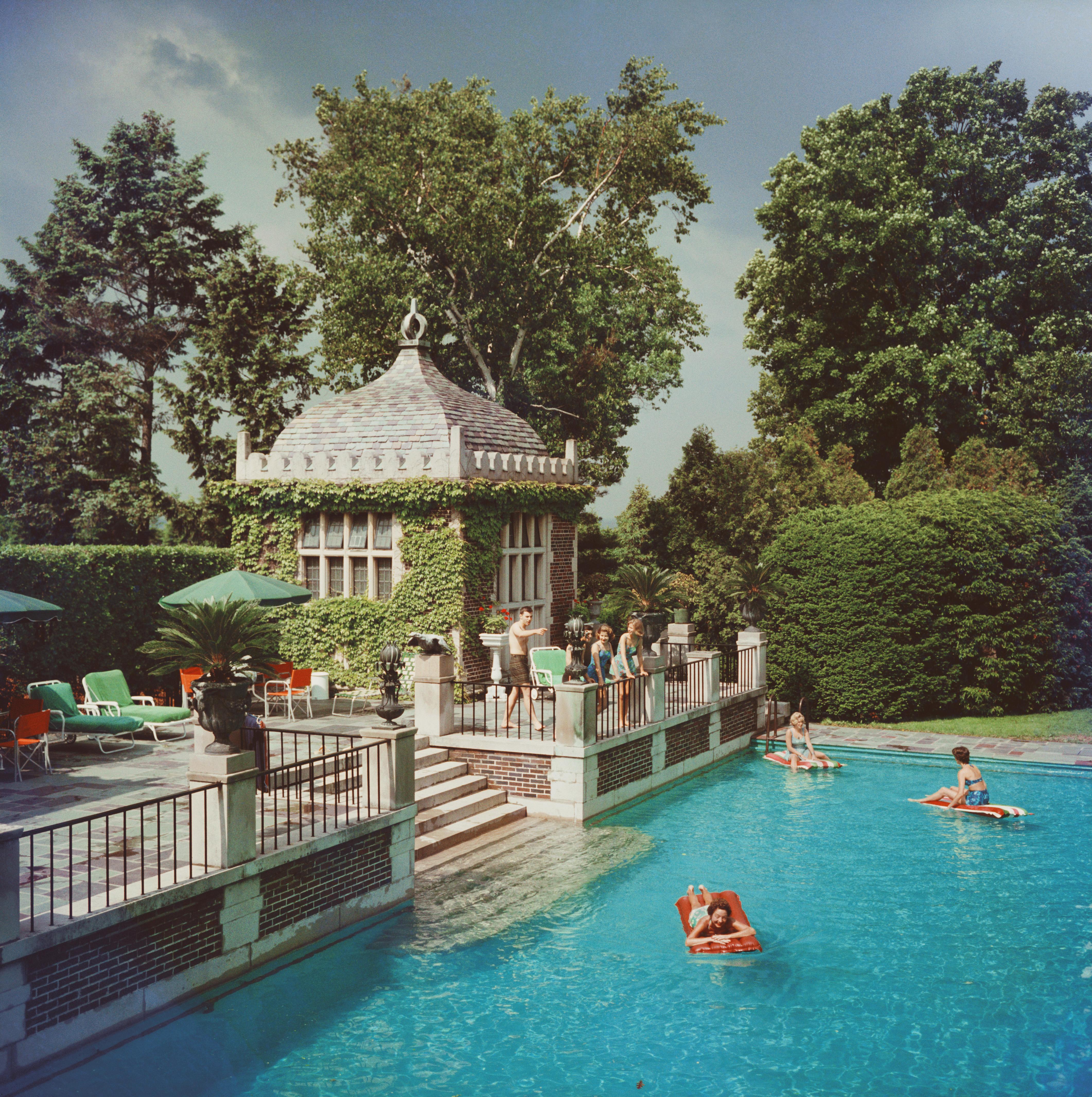 um 1960: Mrs. A. Watson Armour III (Jean Schweppe) mit Freunden und Familie am Pool ihres Anwesens in Lake Forest, Illinois. Eine wunderbare Zeit - Slim Aarons

Schlanke Aarons
Familienbad
Chromogener Lambda-Druck
Später gedruckt
Slim Aarons Estate