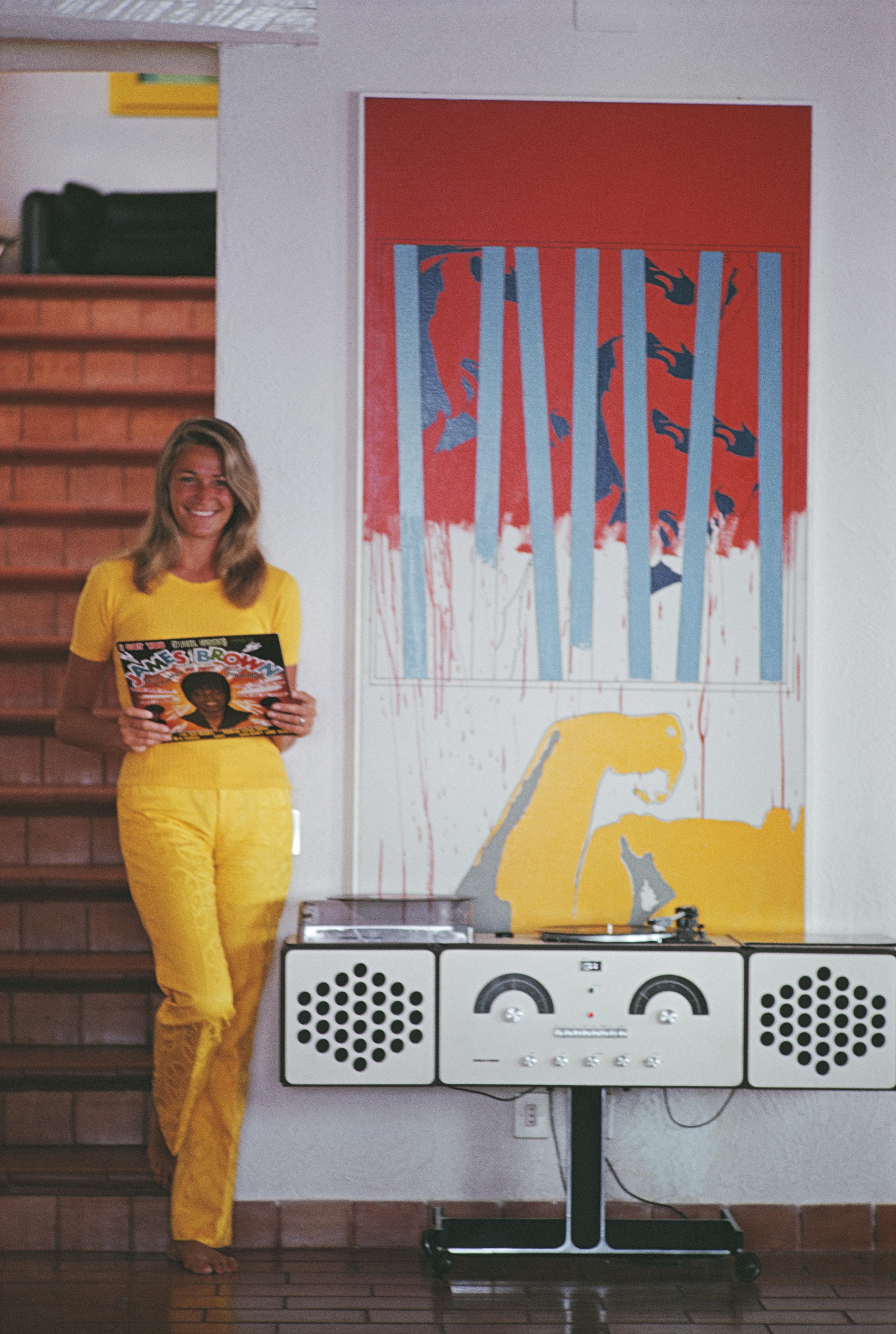 'Funk In Tuscany' 1969 Slim Aarons Limited Estate Edition Print 

Italian fashion designer, model, and socialite, Marta Marzotto (1931 - 2016), playing a James Brown album on an Italian Brionvega Radiofonograph RR126 stereo system, Porto Ercole,