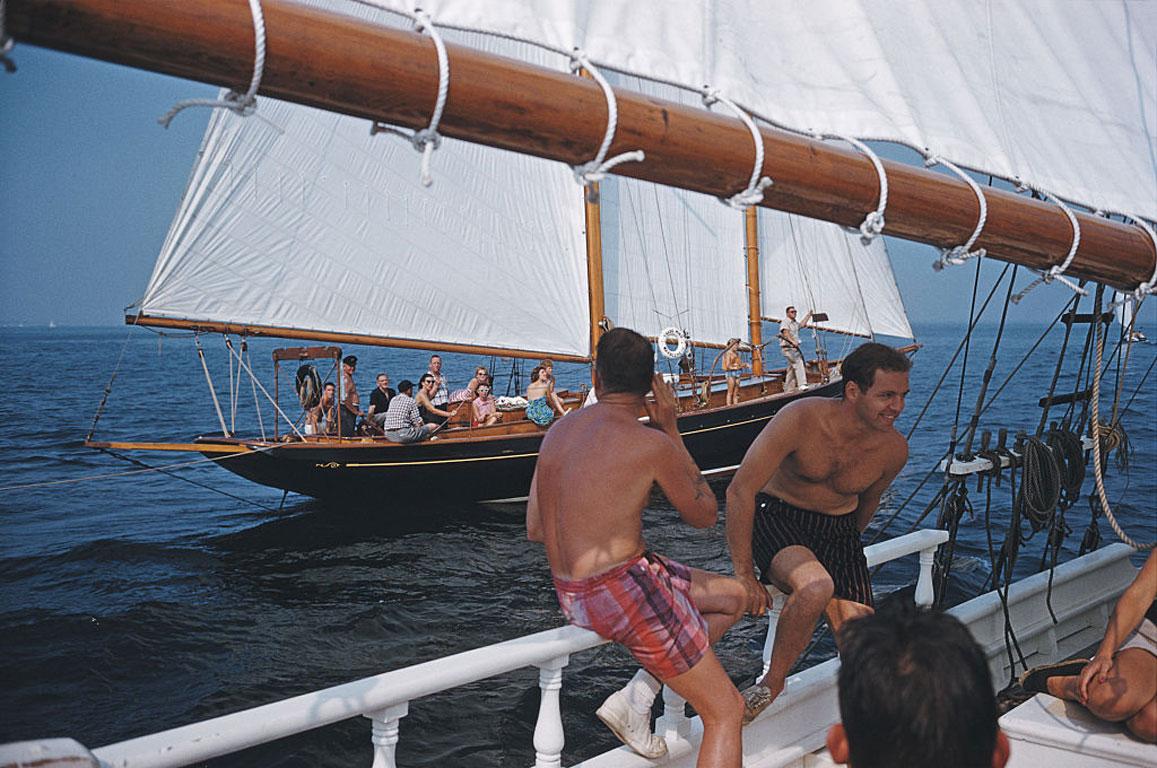 Slim Aarons
Holiday In Boston
1959 (printed later)
C print 
Estate stamped and numbered edition of 150 
with Certificate of authenticity

A sailing holiday on Barclay (Buzzy) H. Warburton III's brigantine 'Black Pearl', 1959. They are sailing off