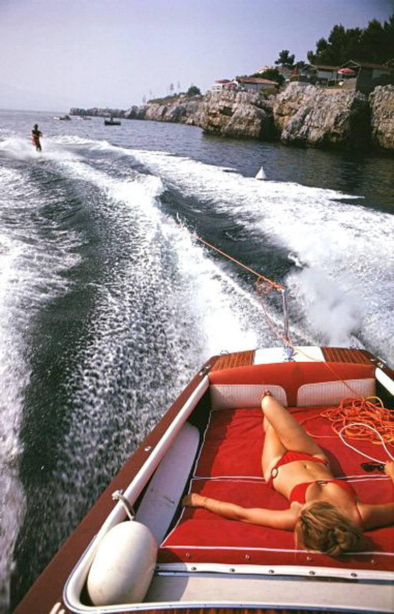 Eine Frau sonnt sich in einem Motorboot, das einen Wasserskifahrer zieht, im Meer vor dem Hotel du Cap Eden-Roc in Antibes an der französischen Riviera, August 1969.

Freizeit in Antibes
Hotel du Cap Eden-Roc, Côte d'Azur
Chromogener