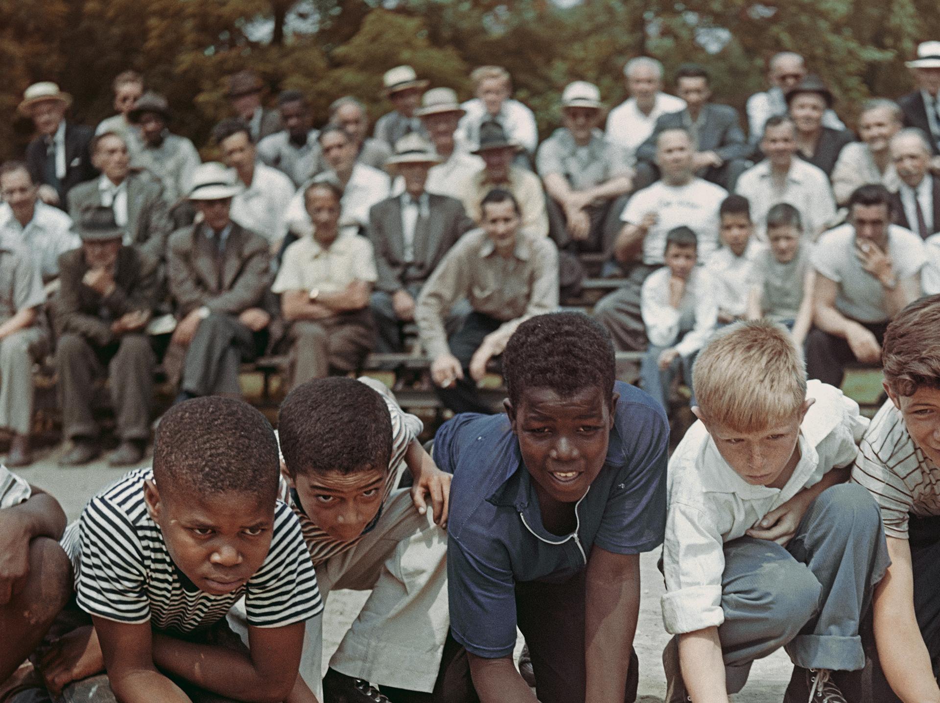 This late 1940s portrait photograph, captured by society photographer Slim Aarons, features a group of boys competing in a marble championship in Central Park, New York City.

This is an estate stamped and hand numbered edition of 150 with