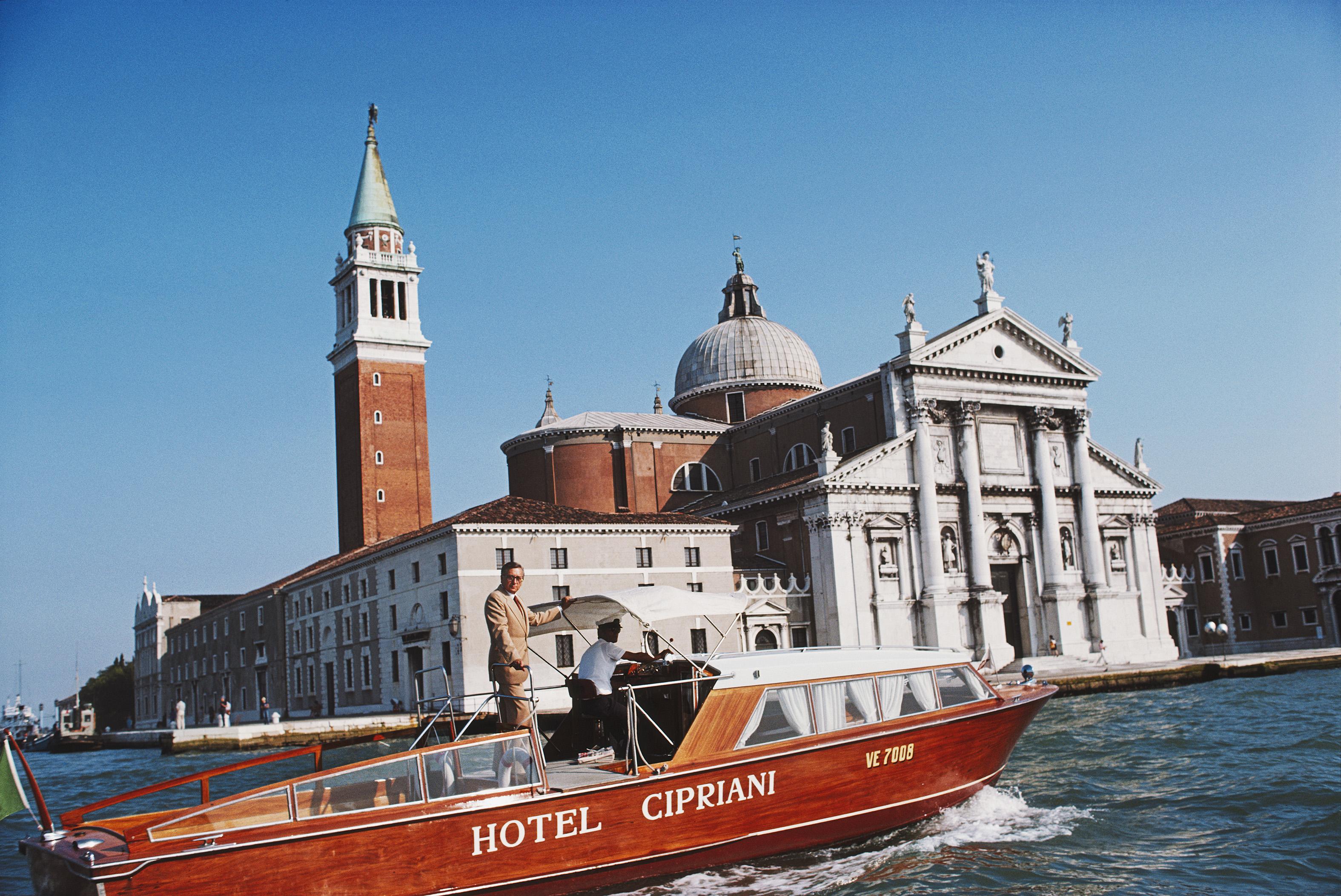 Slim Aarons
Natale Rusconi in Venice
1978 (printed later)
C print 
Signature stamped and numbered edition of 150 
with certificate of authenticity from the Slim Aarons estate 

Natale Rusconi riding a Hotel Cipriani motor launch with the Church of