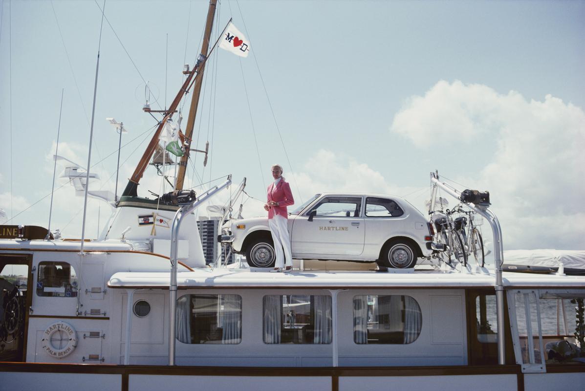 Sin problemas de transporte" 1980 

La Sra. Woolworth Donahue con coche y bicicletas en su yate a motor, 'Hartline'. 

101 x 152 cm Tamaño del papel 
 
Colección de sellos patrimoniales Edición limitada a 150 

Foto de Slim Aarons

Impreso en