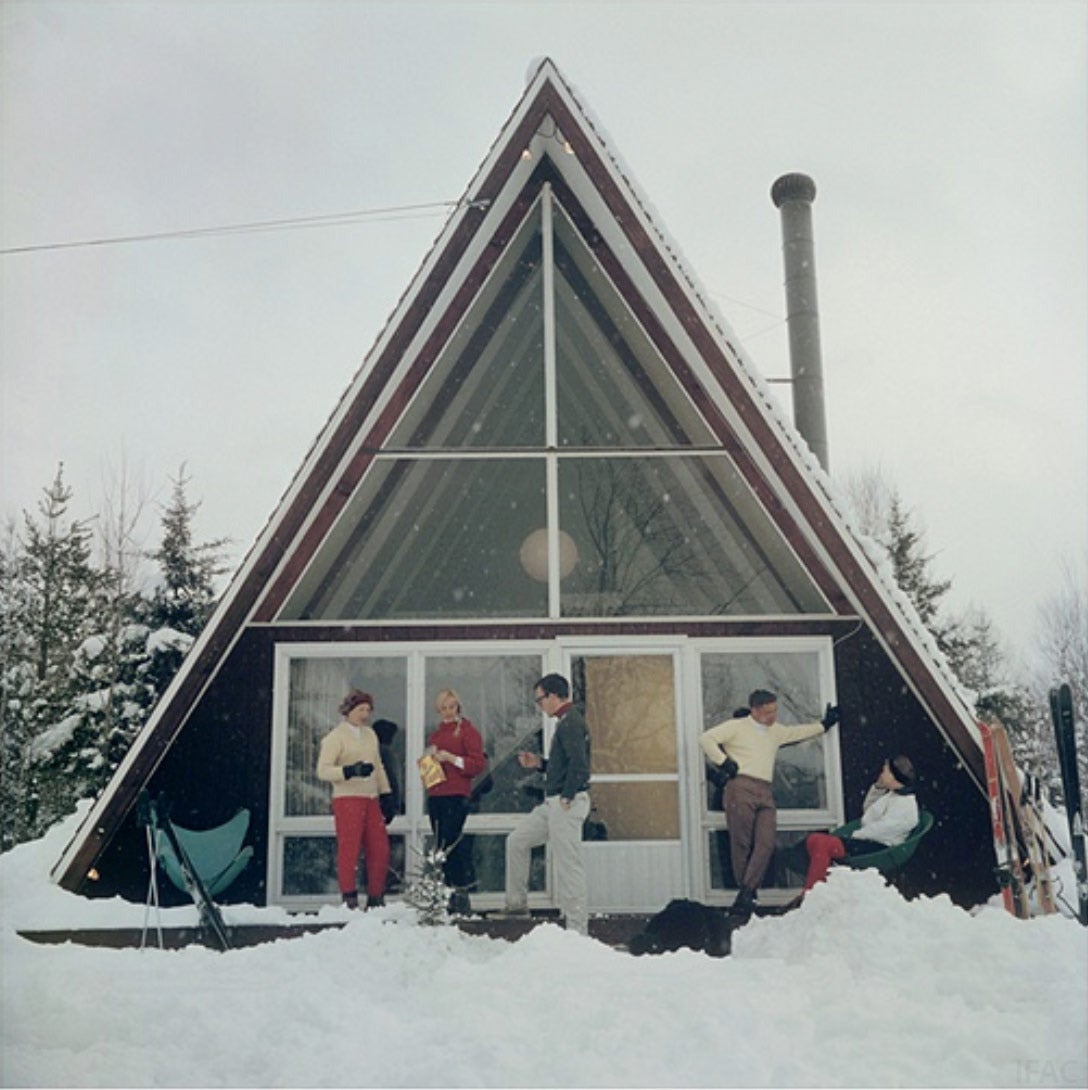 Fünf Personen entspannen sich auf der Terrasse des dreieckigen Skaal House mit Glasfassade im Skigebiet Stowe Mountain in Stowe, Vermont, 1962. Eigentümerin des Grundstücks ist Doris Molliel, die links von der Gruppe steht.

Nachlassgestempelte und