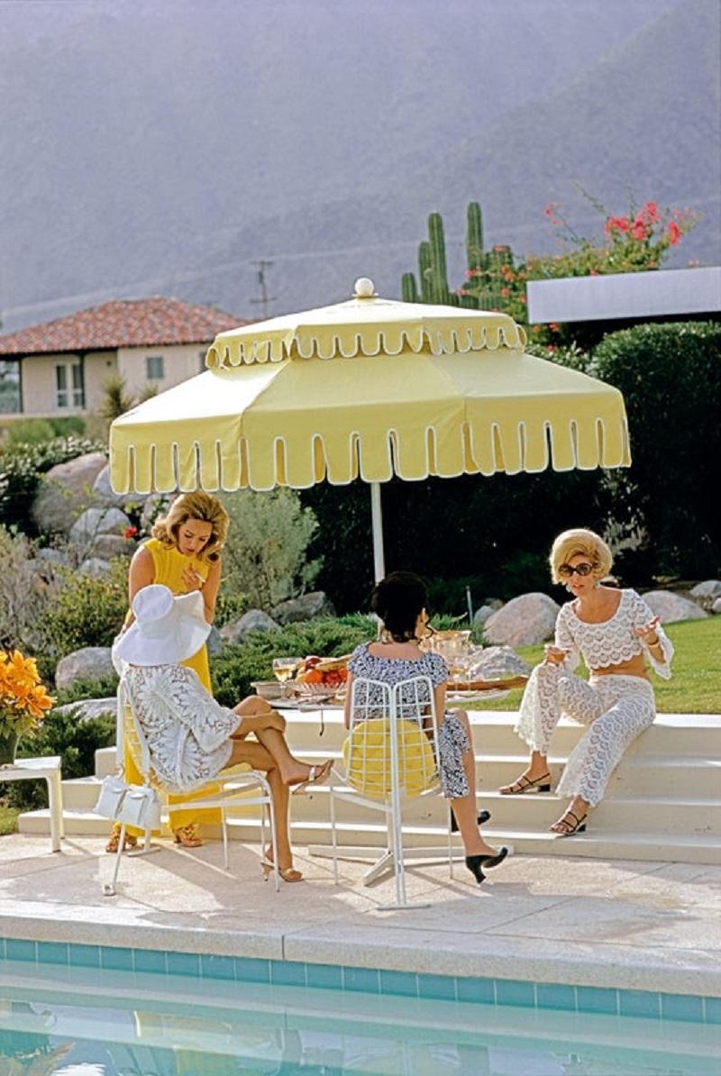 'Palm Springs Life' 1970 Slim Aarons Limited Estate Edition Print 

Nelda Linsk (left, in yellow), wife of art dealer Joseph Linsk with guests by the pool at the Linsk's desert house in Palm Springs, January 1970. At far left in white sunhat is