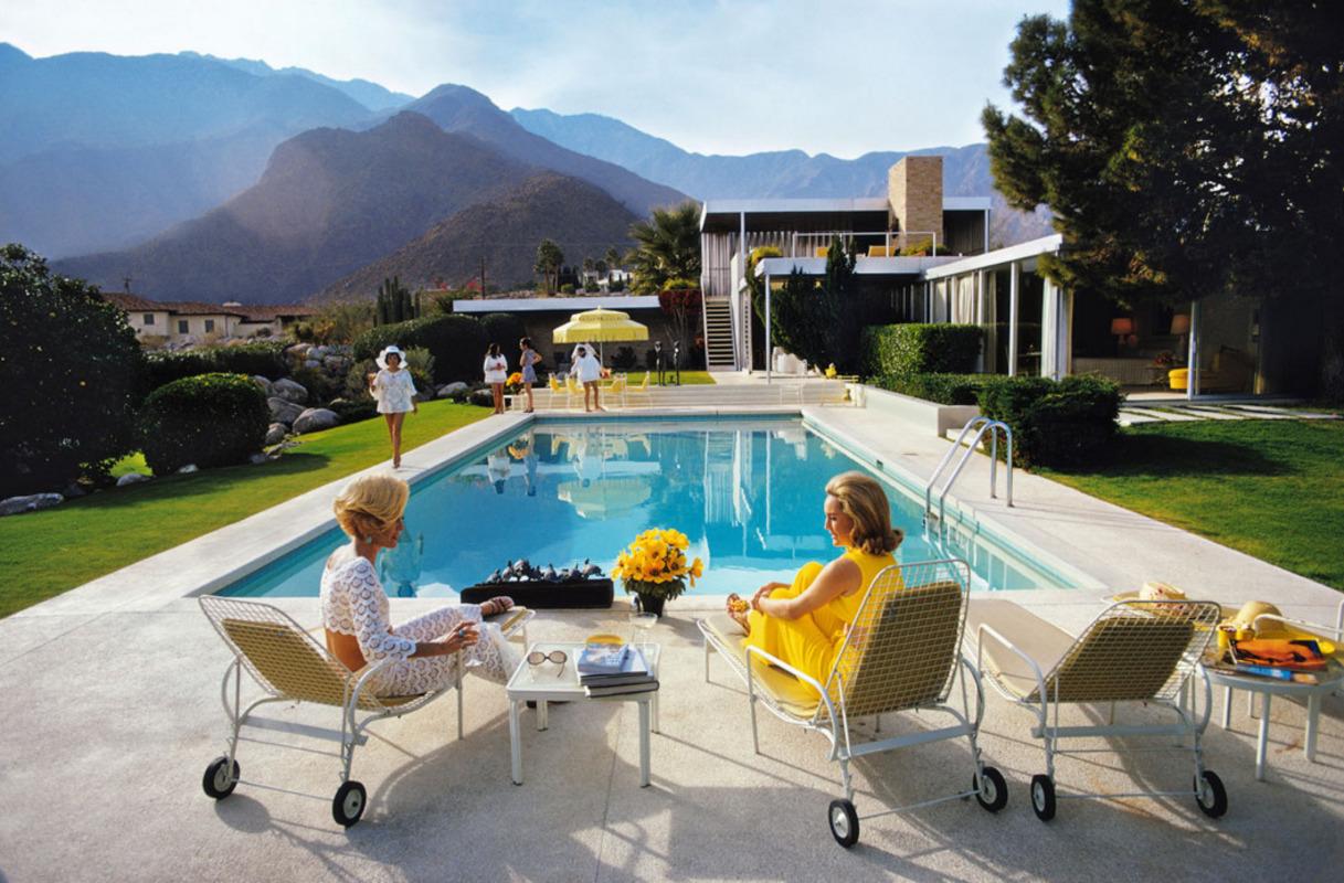 Poolside Glamour, 1970 by Slim Aarons, Printed Later.
A desert house designed by Richard Neutra for Edgar J. Kaufmann, Palm Springs, California, January 1970. Lita Baron approaches, while in the foreground Nelda Linsk (right) wife of art dealer